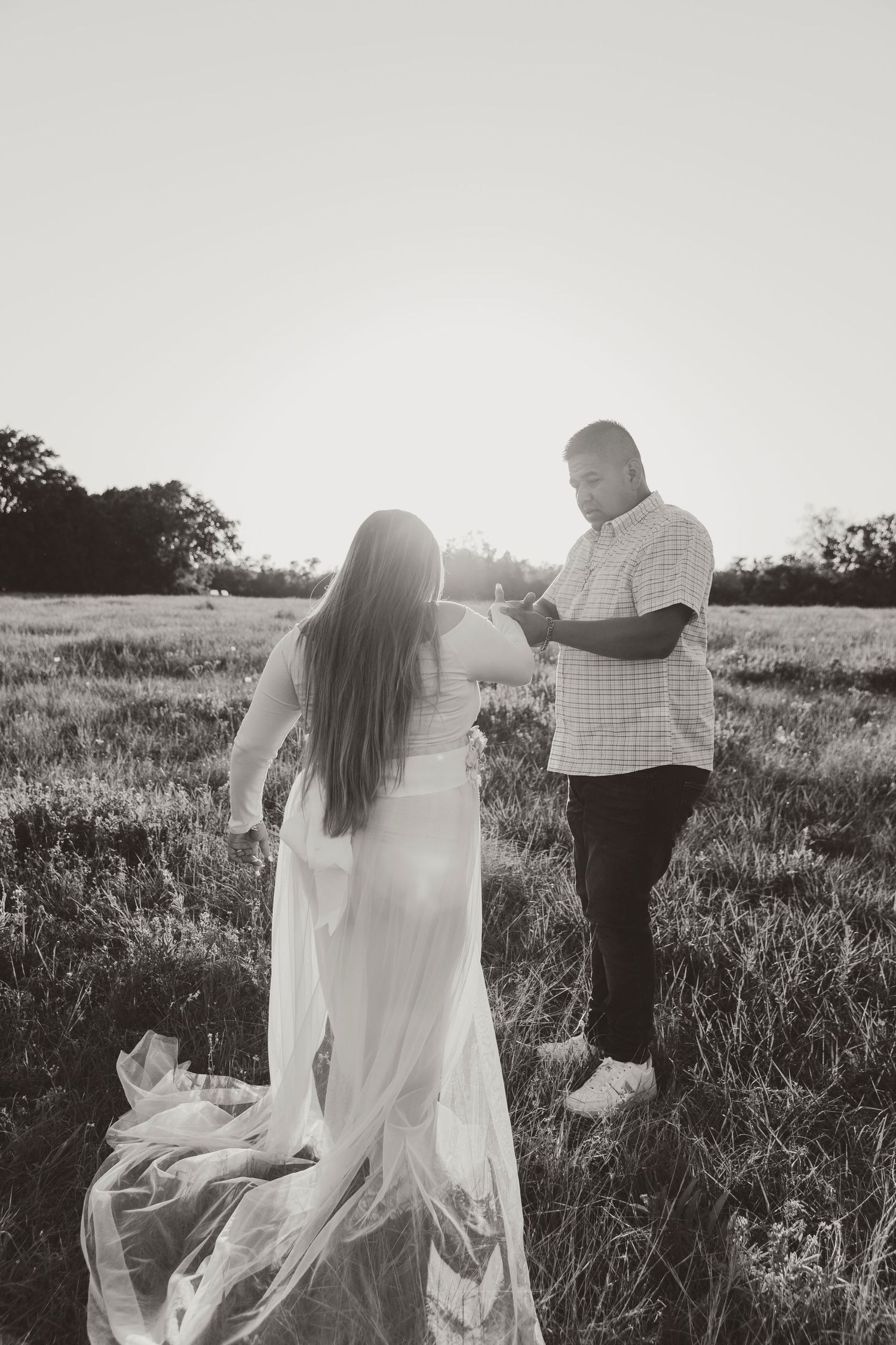 Couple in a field at sunset during a romantic maternity photoshoot.