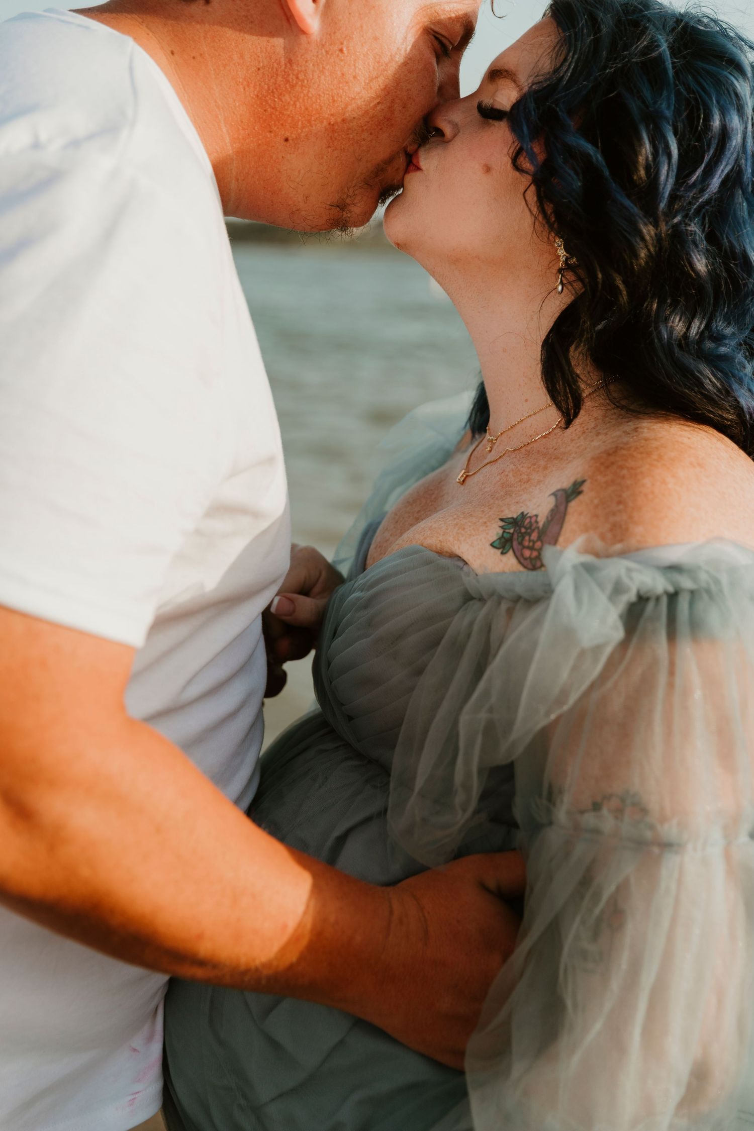 A romantic couple shares an intimate moment in tender embrace at a beach setting.