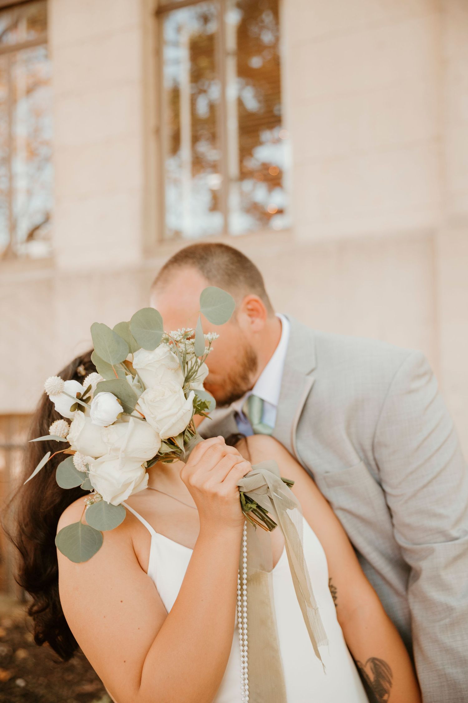 A romantic wedding moment captured in a series of three photos showing a couple kissing with white floral bouquet details.