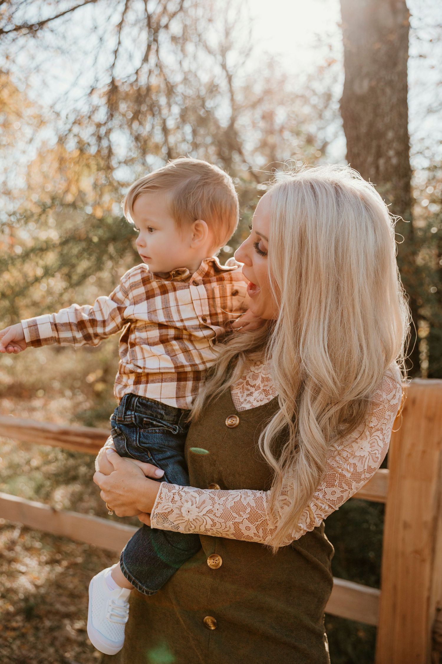 A warm autumn scene shows a tender moment between parent and child on a wooden bench during golden hour.