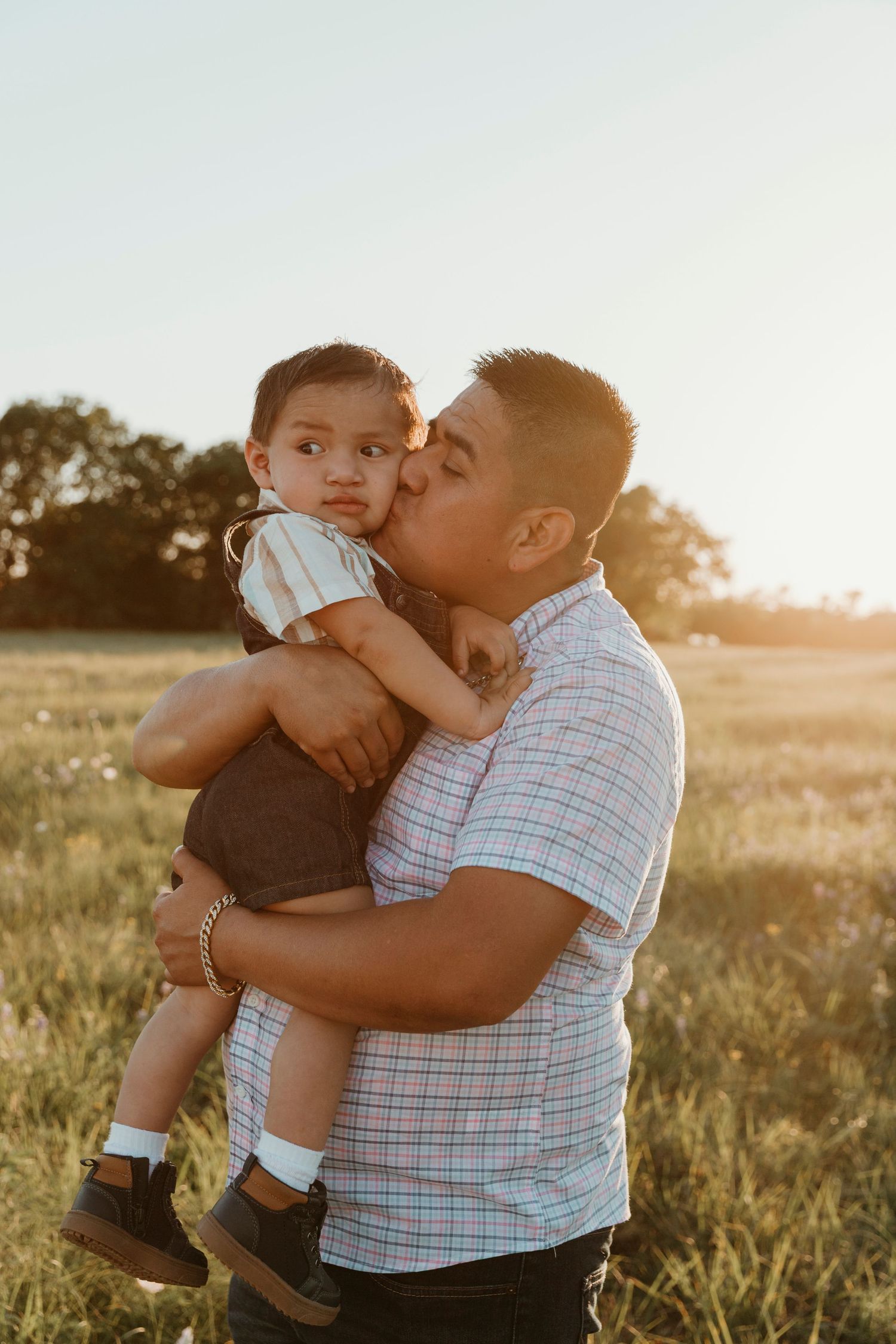 Tender family moment between parent and child in a golden sunset field.
