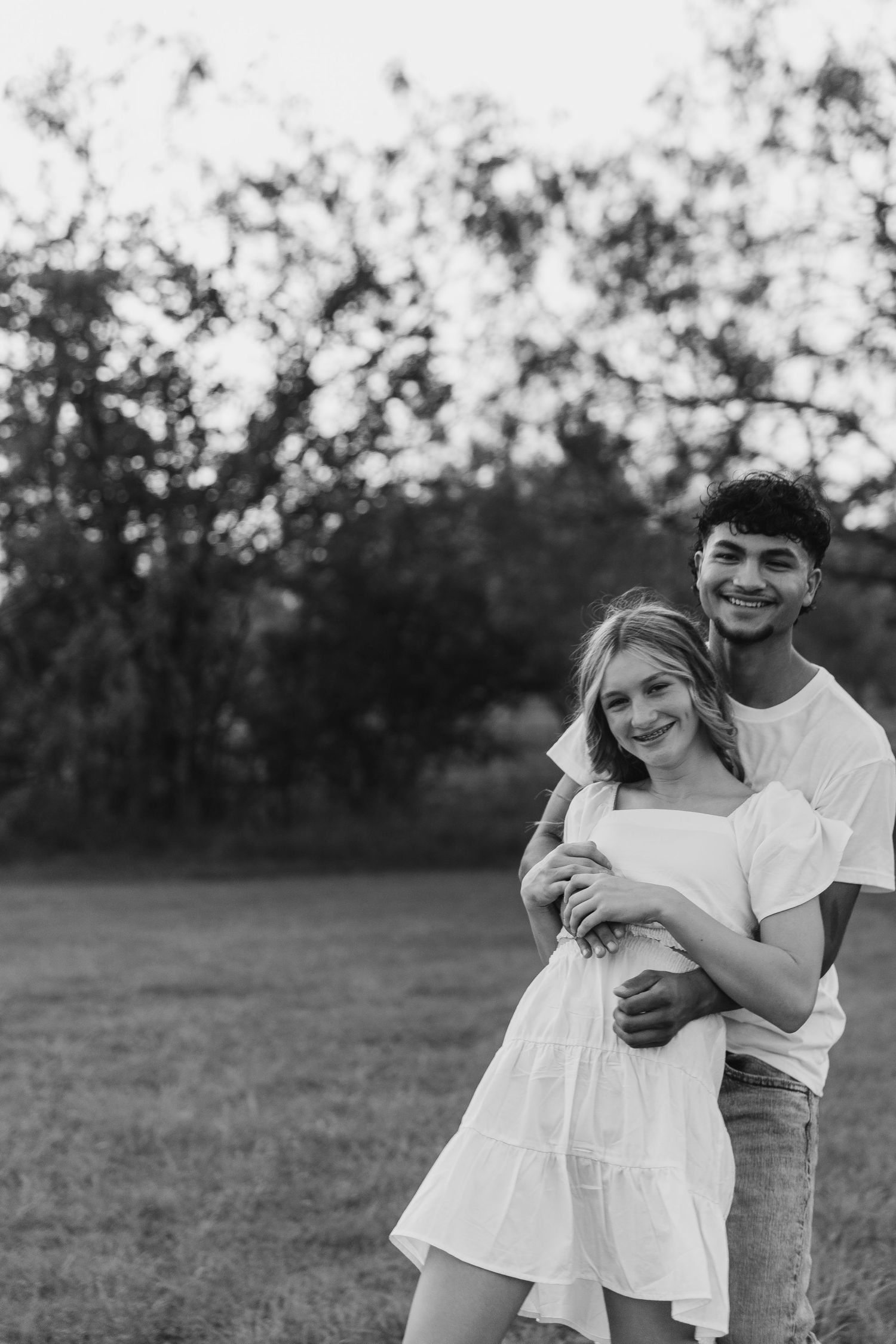 Black and white photo series of a couple embracing and laughing together outdoors.