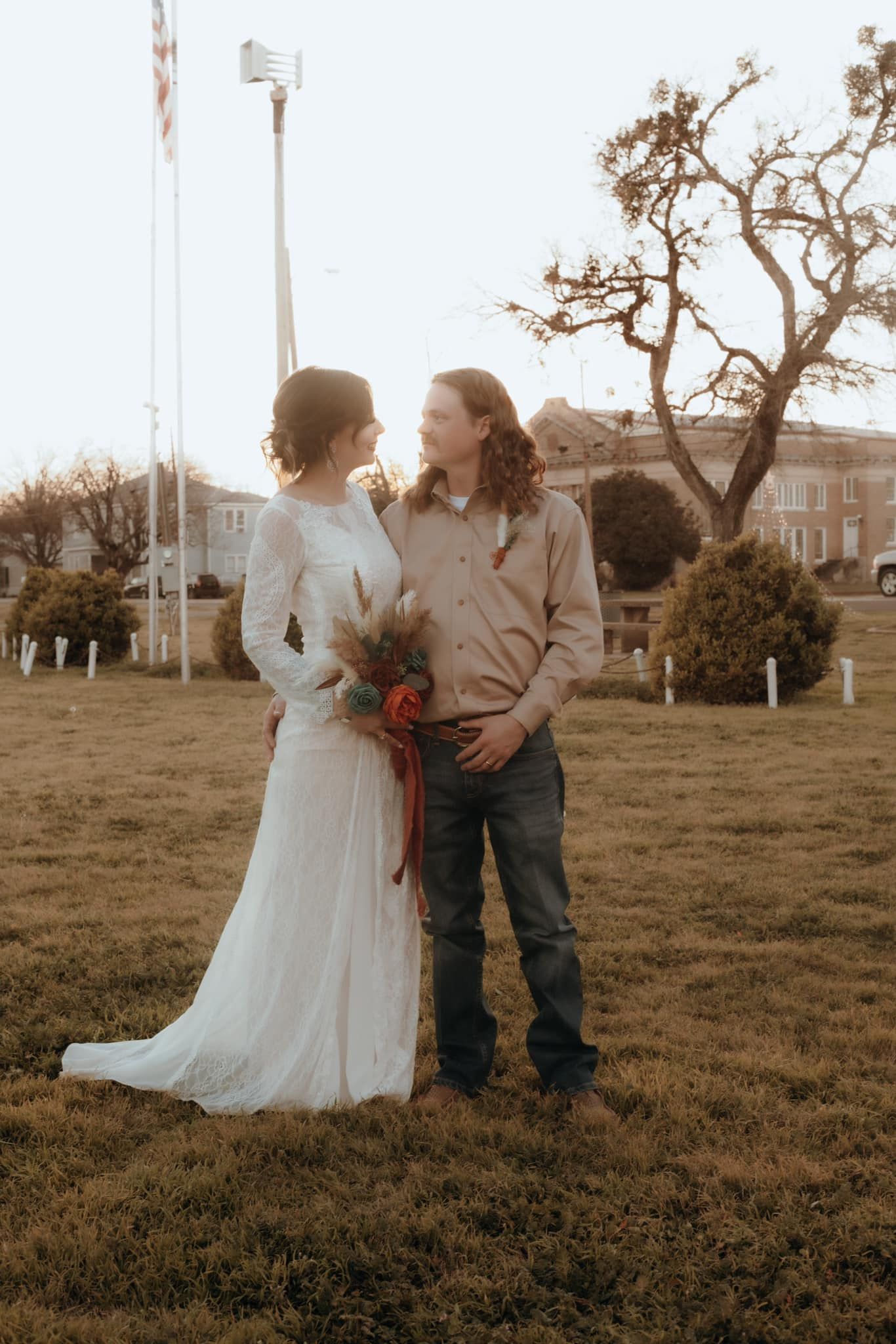 Bride and groom share intimate moment in rustic outdoor setting.