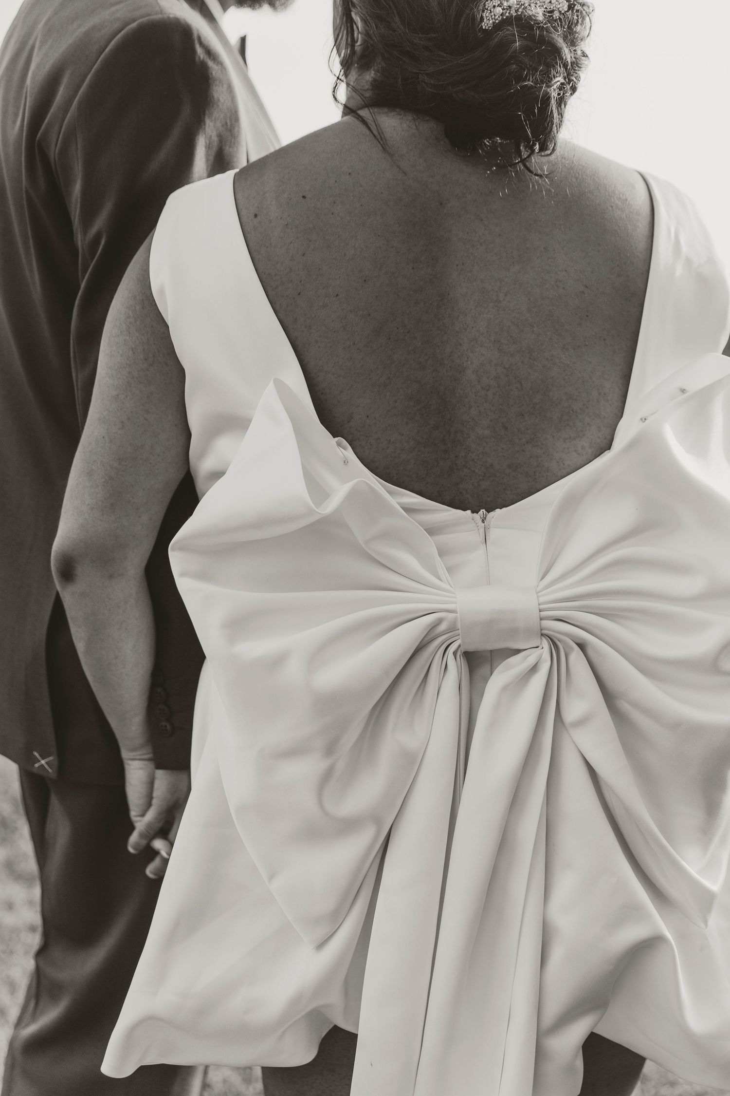 Detail shot of elegant white wedding dress with dramatic bow detail on the back.
