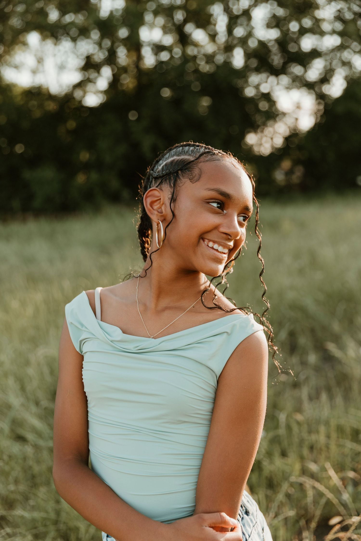 A graceful pose in mint blue top against a natural outdoor setting during sunset.