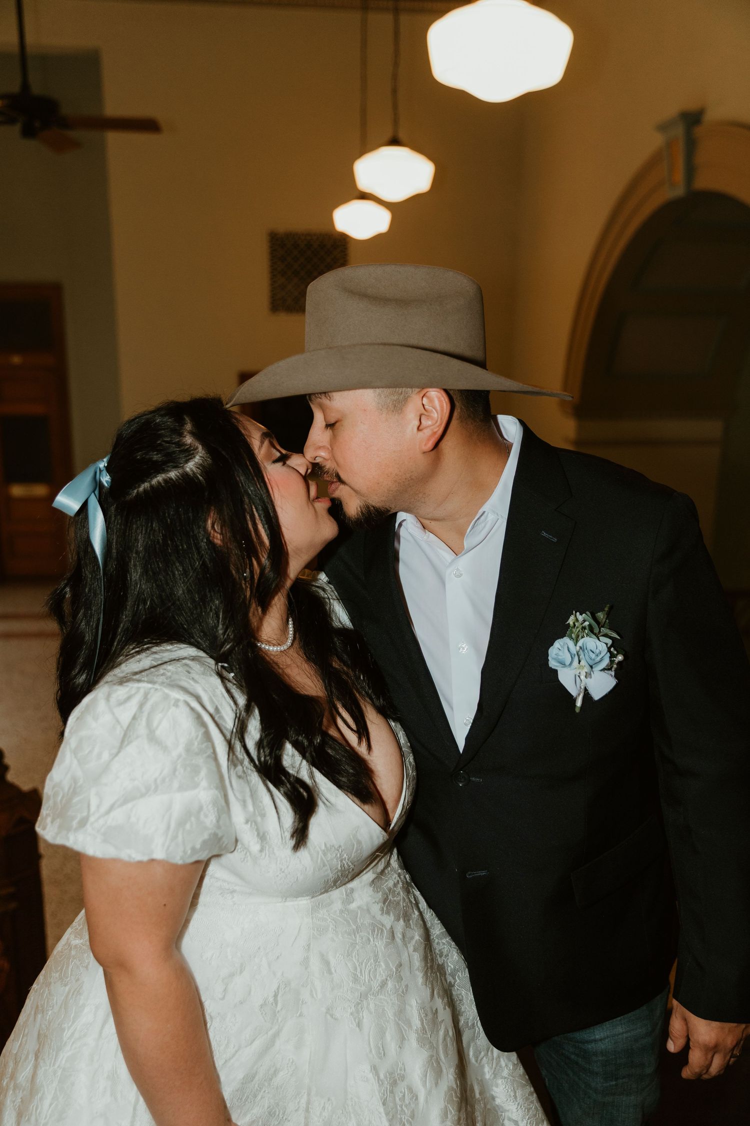An intimate wedding moment captured indoors with warm lighting and decorative pendant lamps.