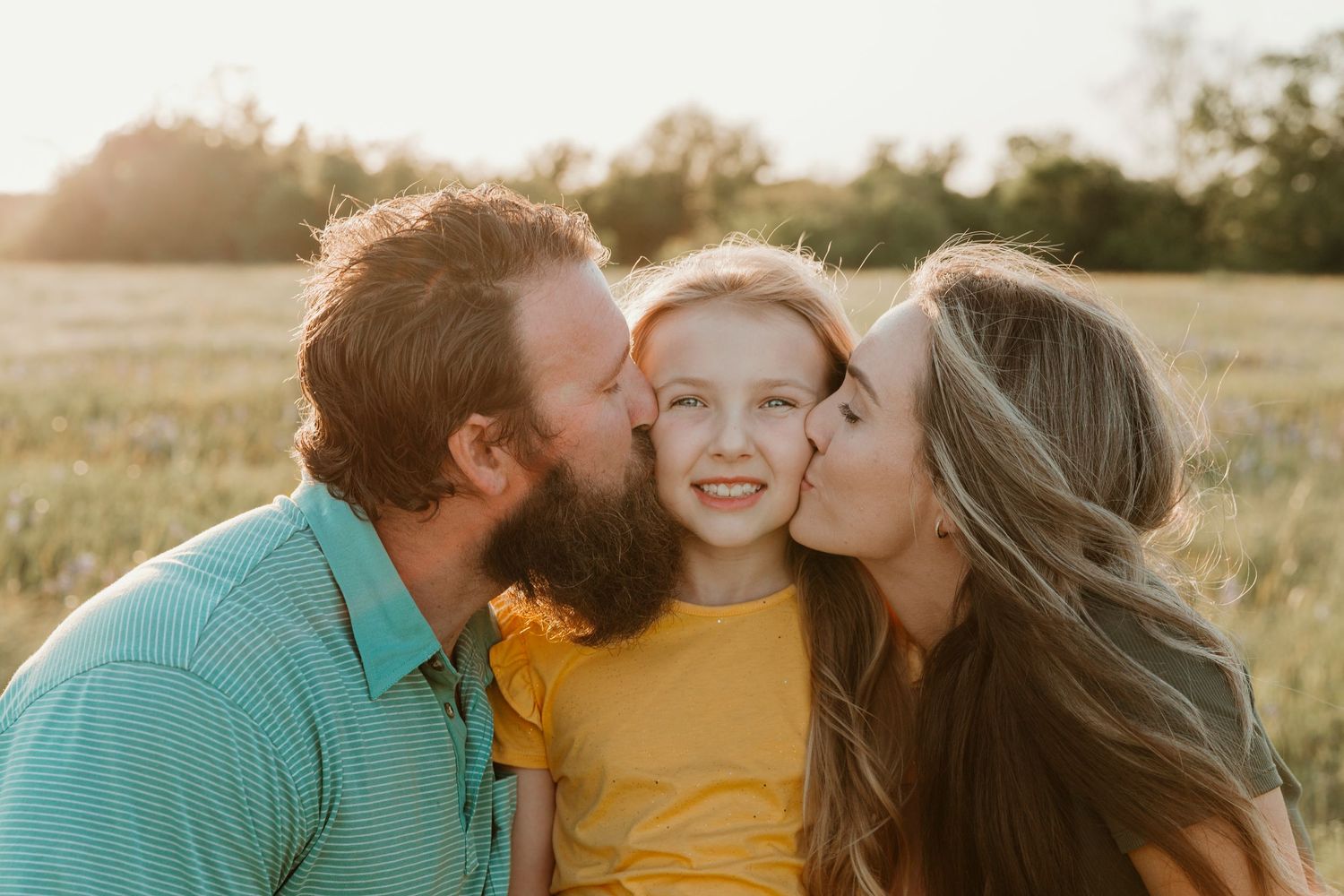 Sweet family moment captured during sunset in a meadow.
