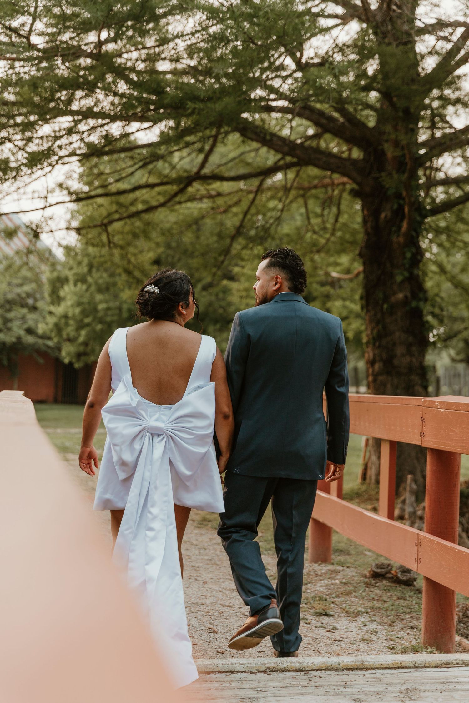 Couple walking along a wooden bridge path surrounded by trees.