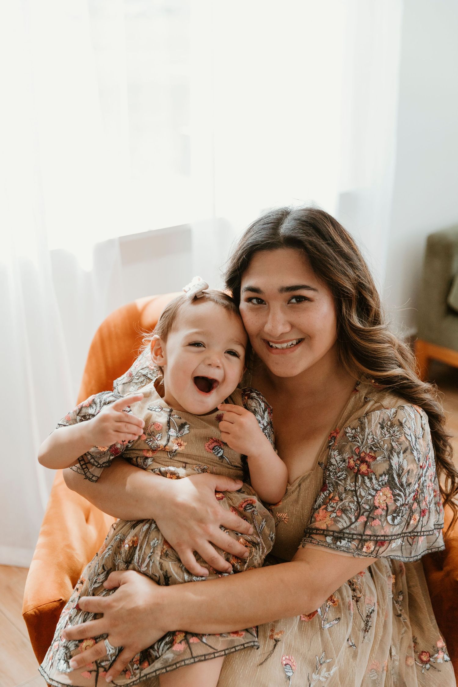 A sweet candid moment shared between parent and child on a bright sofa with natural lighting coming through windows.