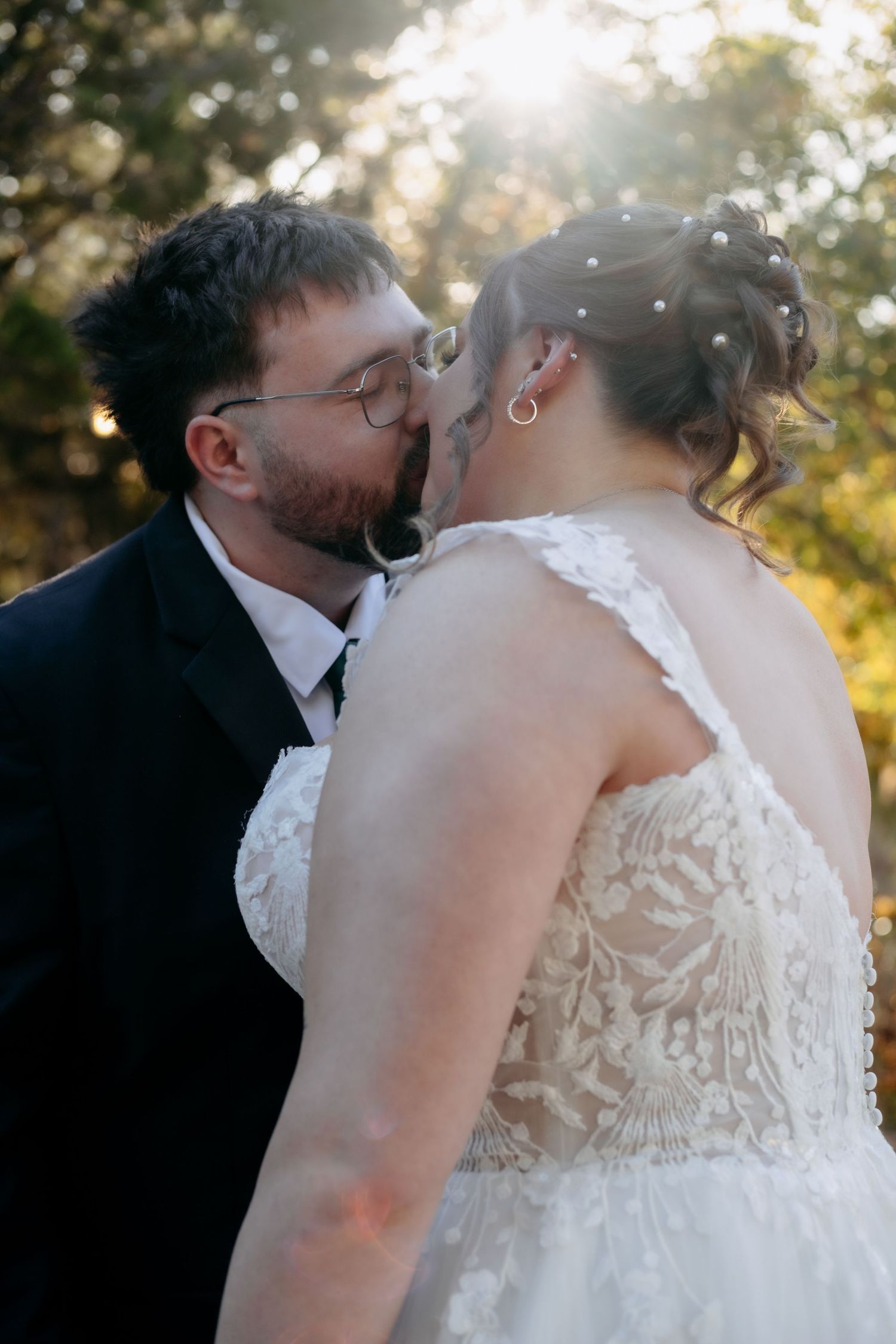Intimate wedding kiss photographed in warm sunset lighting.