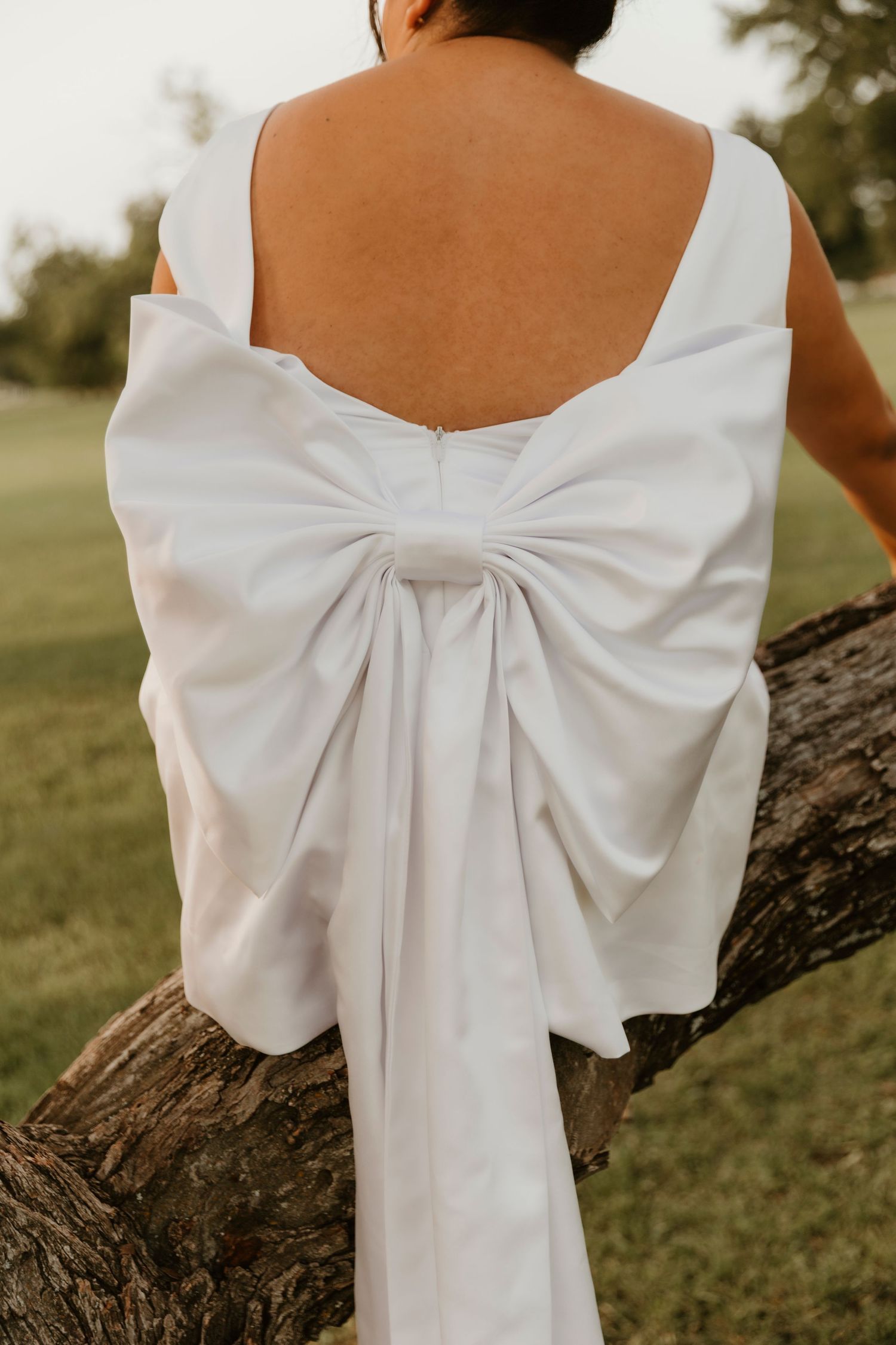 Close up of a white bow detail on the back of a sleeveless wedding dress.