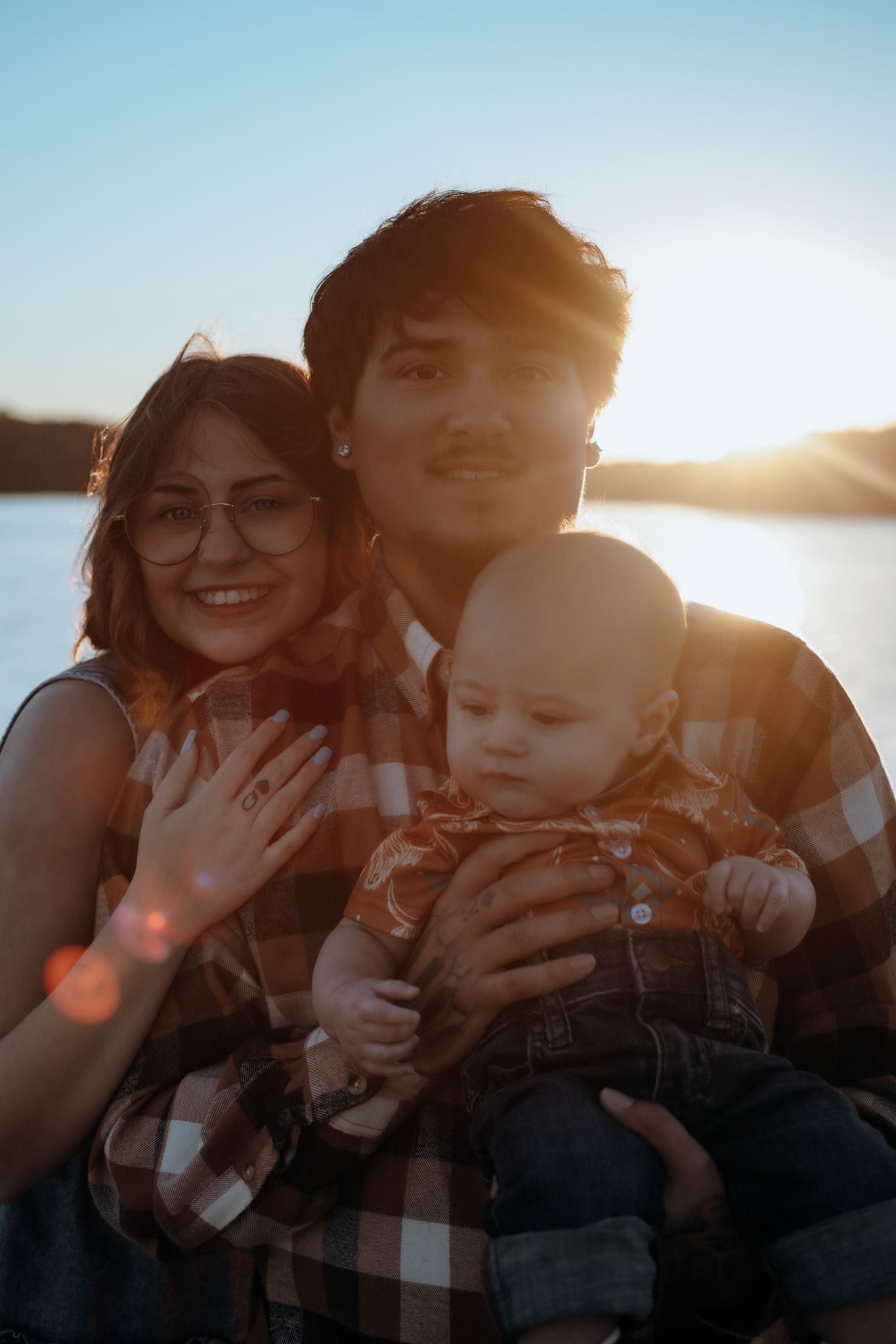 Family portrait taken during golden hour with sun flare and bright smiles.