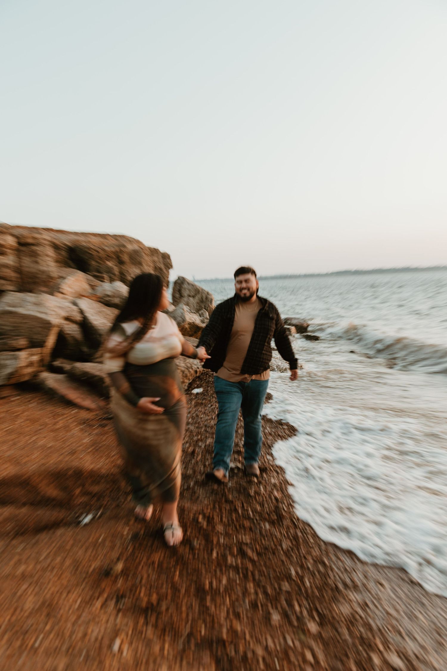 Artistic motion blur photograph of people on a beach with rocks and ocean waves.