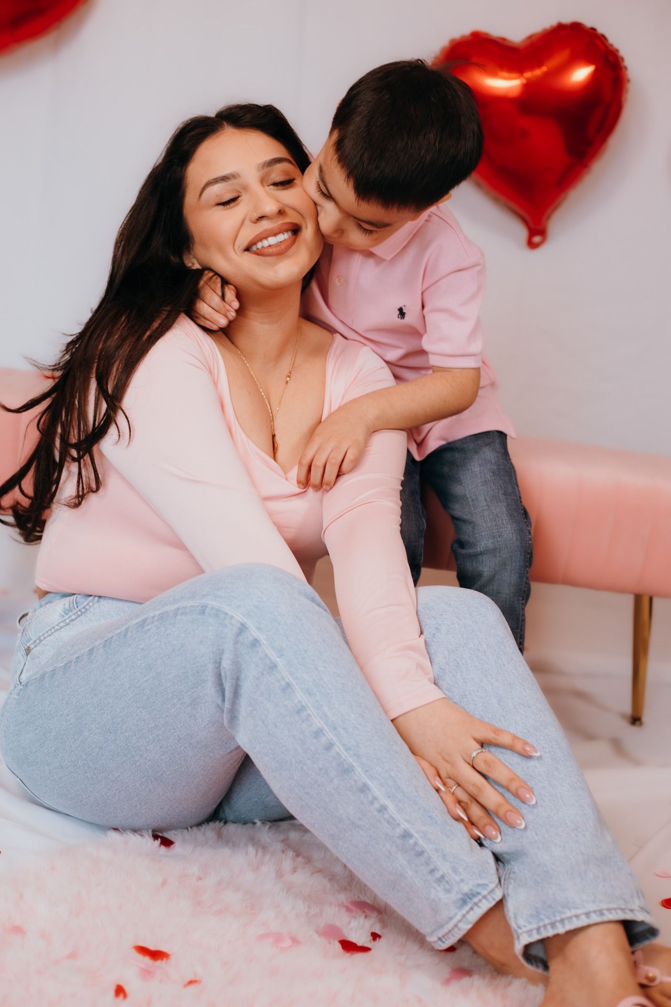A playful moment with pink and red heart balloons in the background on a pink fluffy rug.