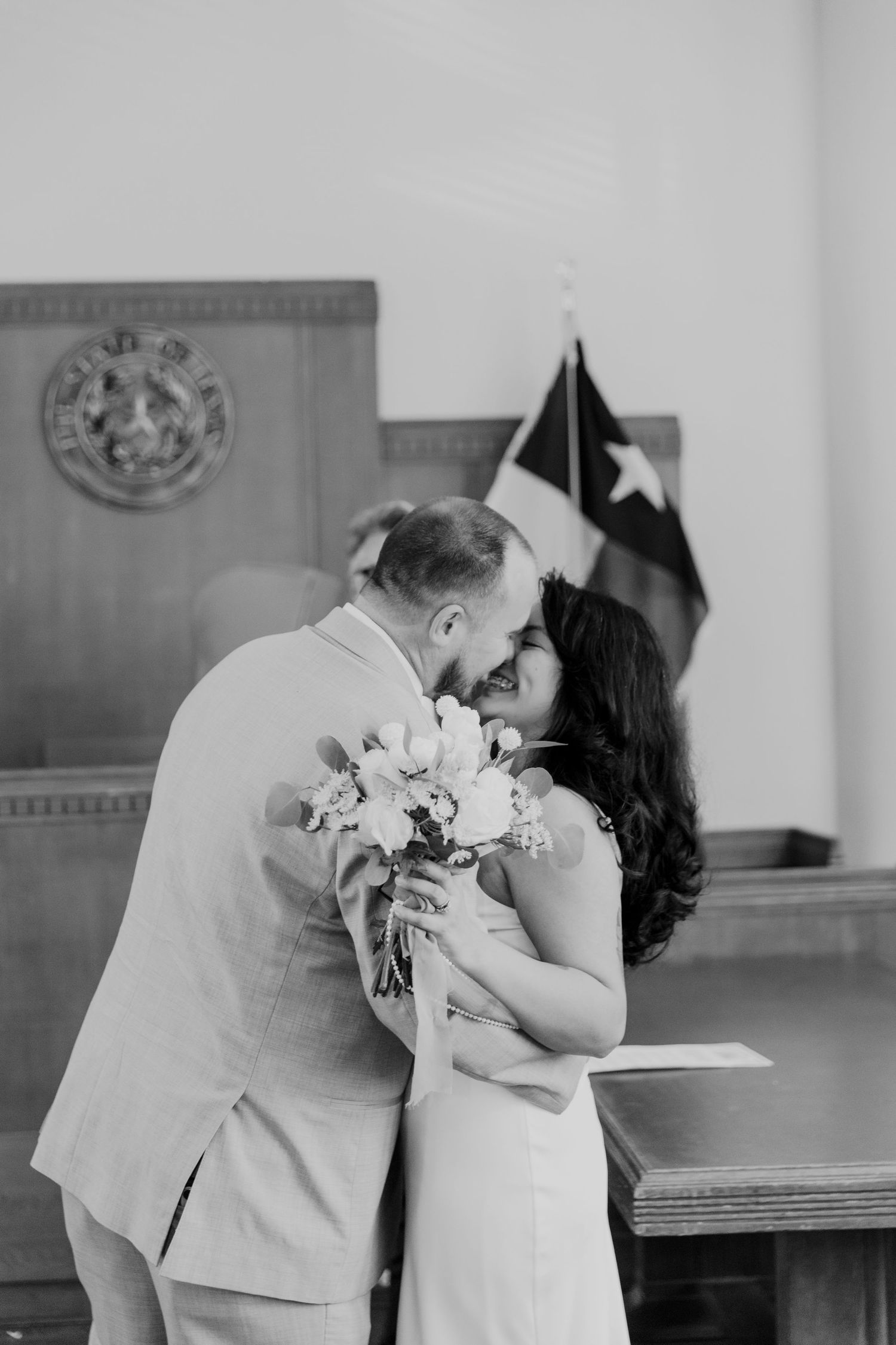 Black and white wedding photos showing tender moments between newlyweds with a white bouquet in an indoor setting.