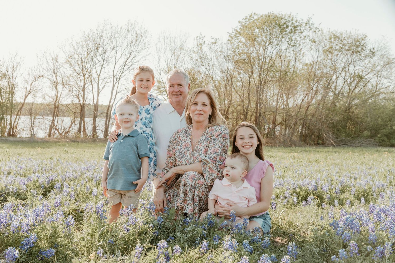 Family portrait session in a blooming bluebonnet field during golden hour.