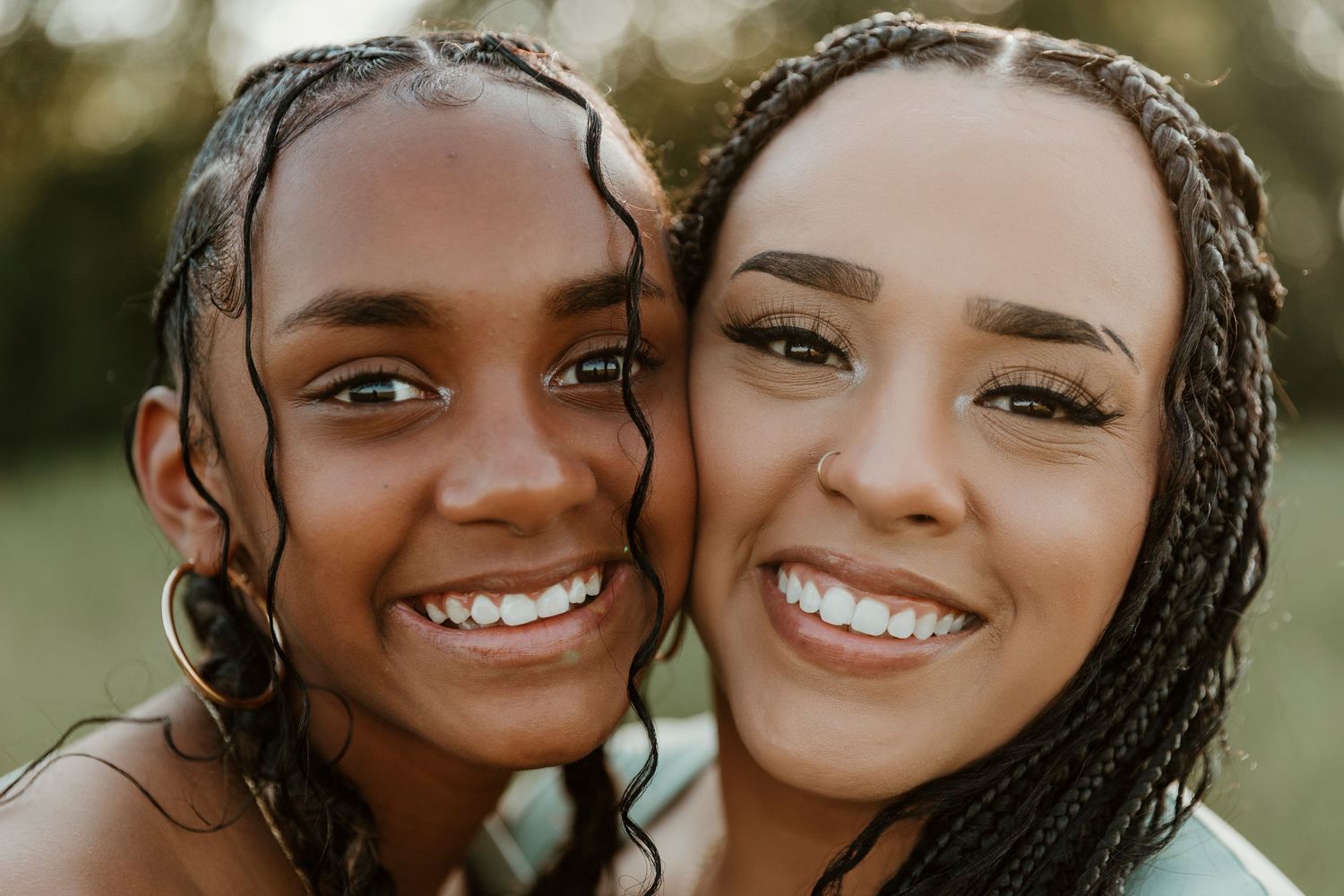 Two friends share bright smiles in a close-up portrait outdoors.