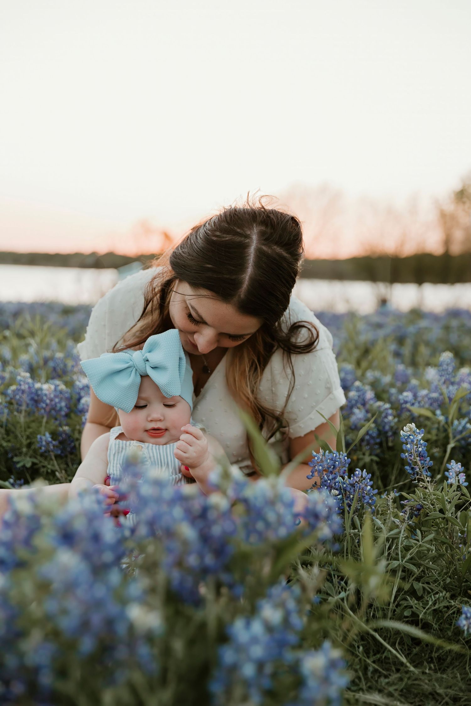Sweet interaction between parent and child in a field of blue wildflowers at dusk.