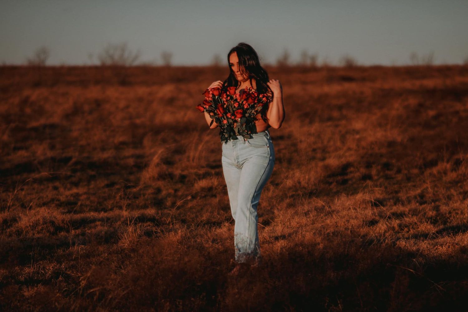 Person in white clothing standing in a golden field at sunset with warm lighting.