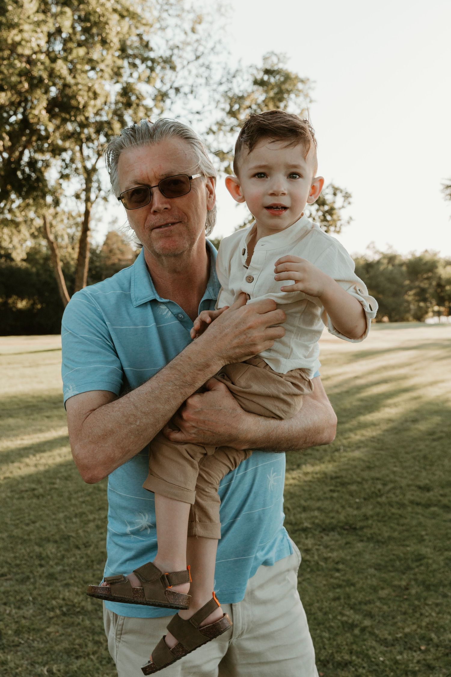 A playful interaction between generations captured in warm evening light outdoors.