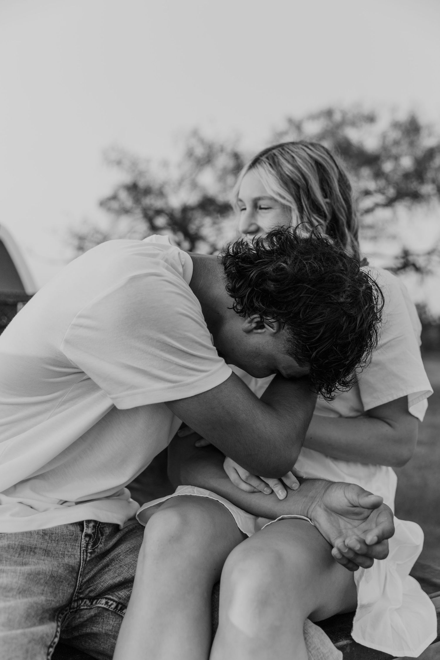 A tender black and white portrait of a couple sharing an intimate embrace outdoors.