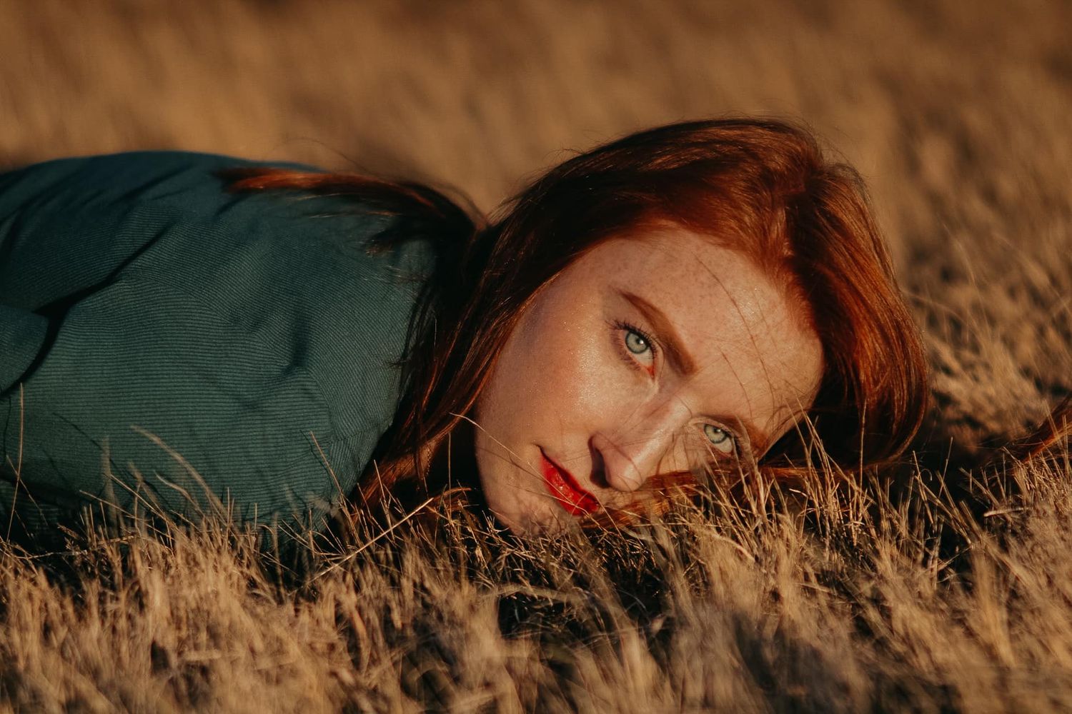 Artistic portrait lying in golden autumn grass during sunset.