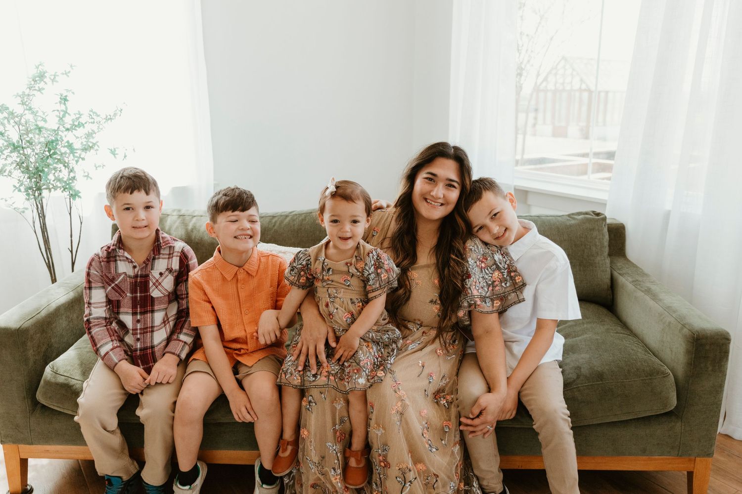 Candid family photo showing group in coordinated outfits sitting close together on sofa.