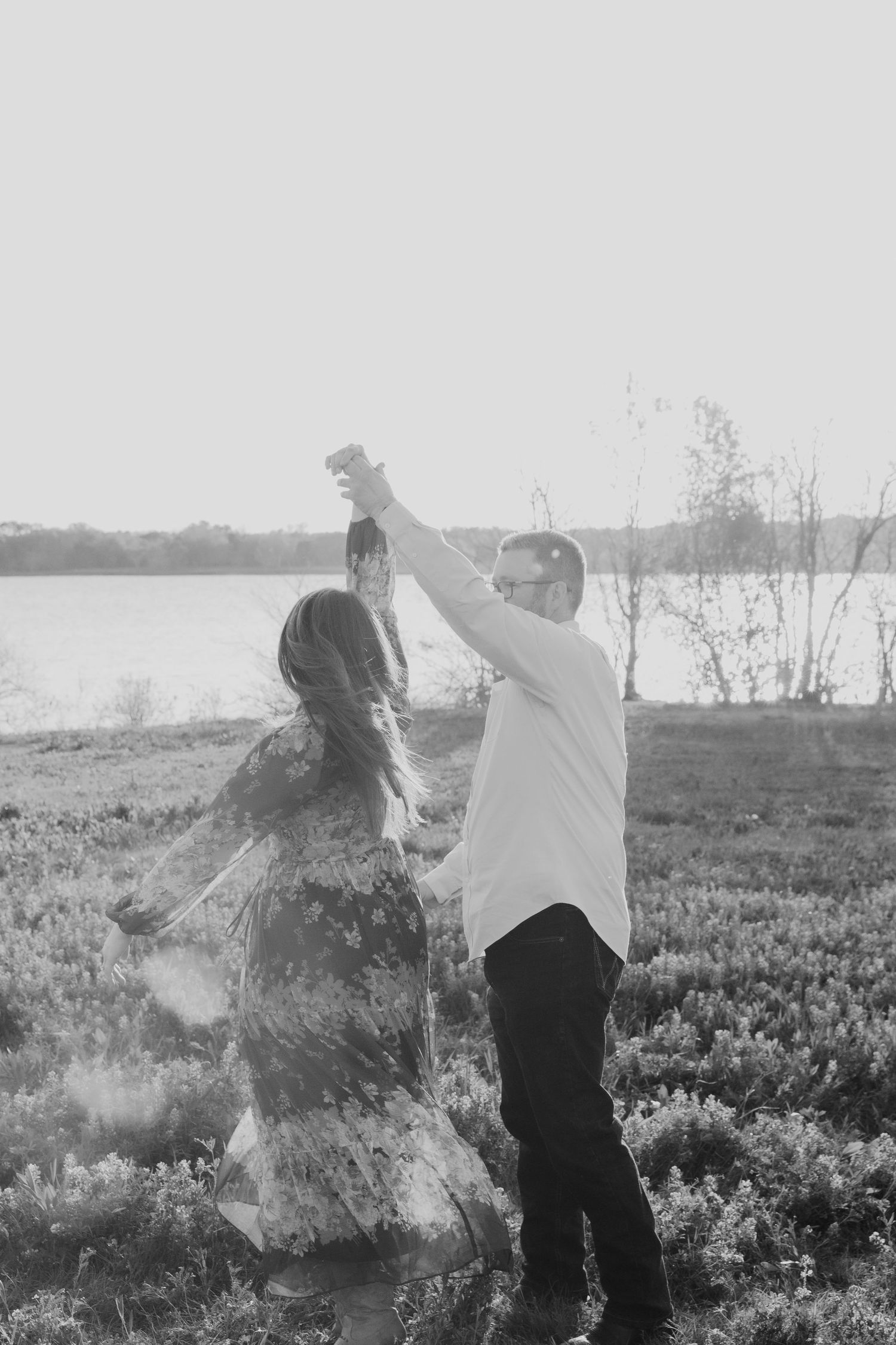 Artistic black and white photo of couple dancing in a wildflower meadow.