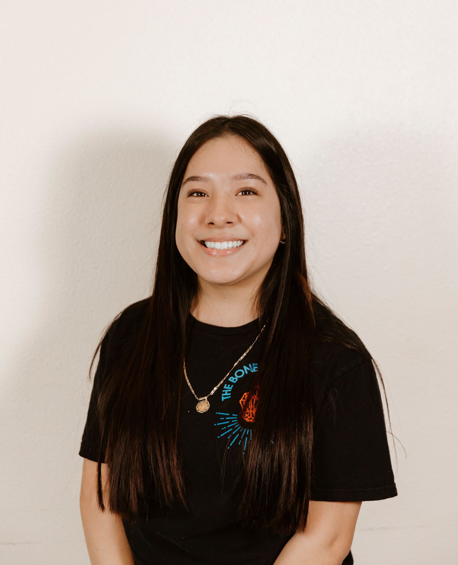 Professional portrait of person wearing black shirt with decorative necklace.