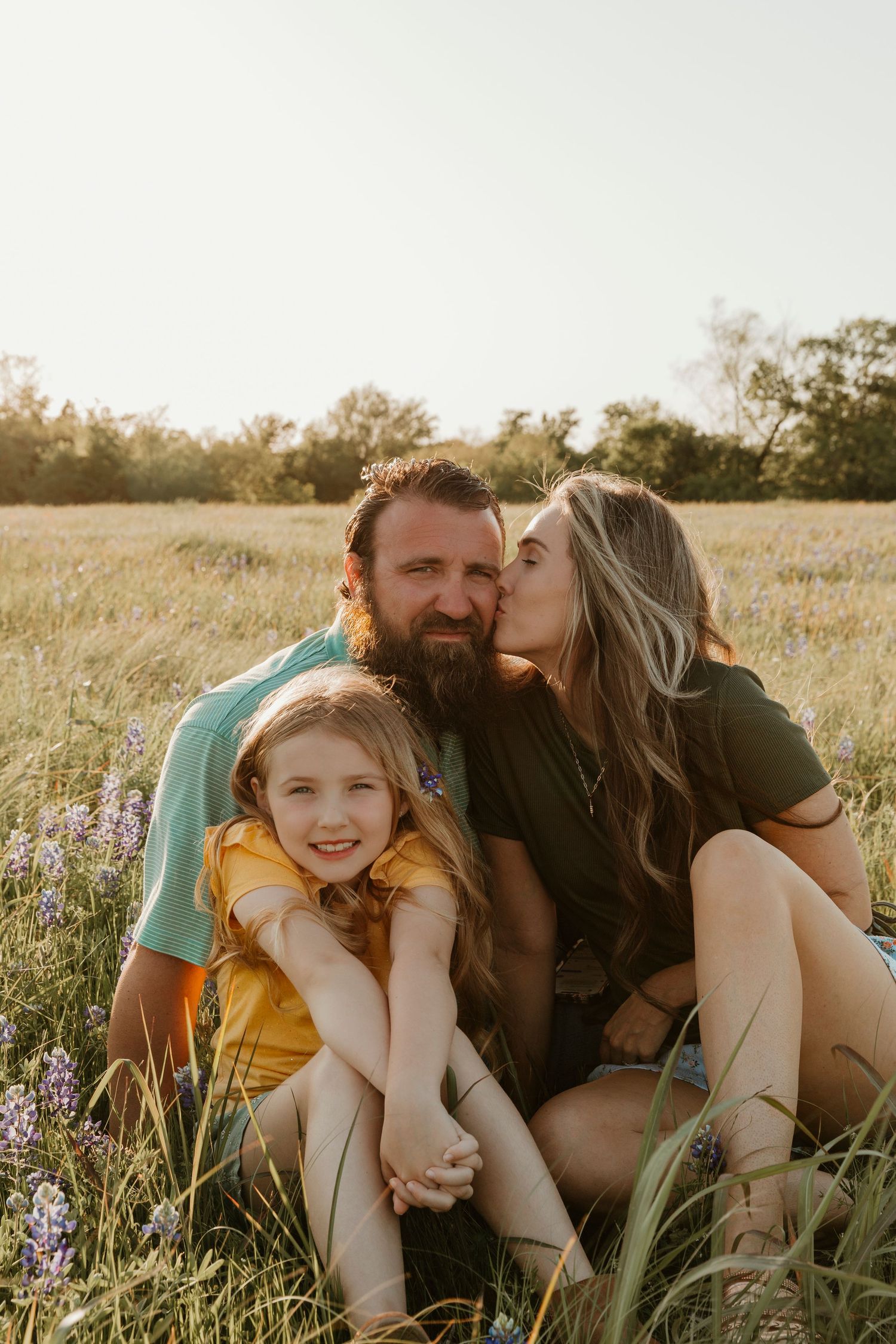 Family enjoying a playful moment together in a wildflower field at sunset.