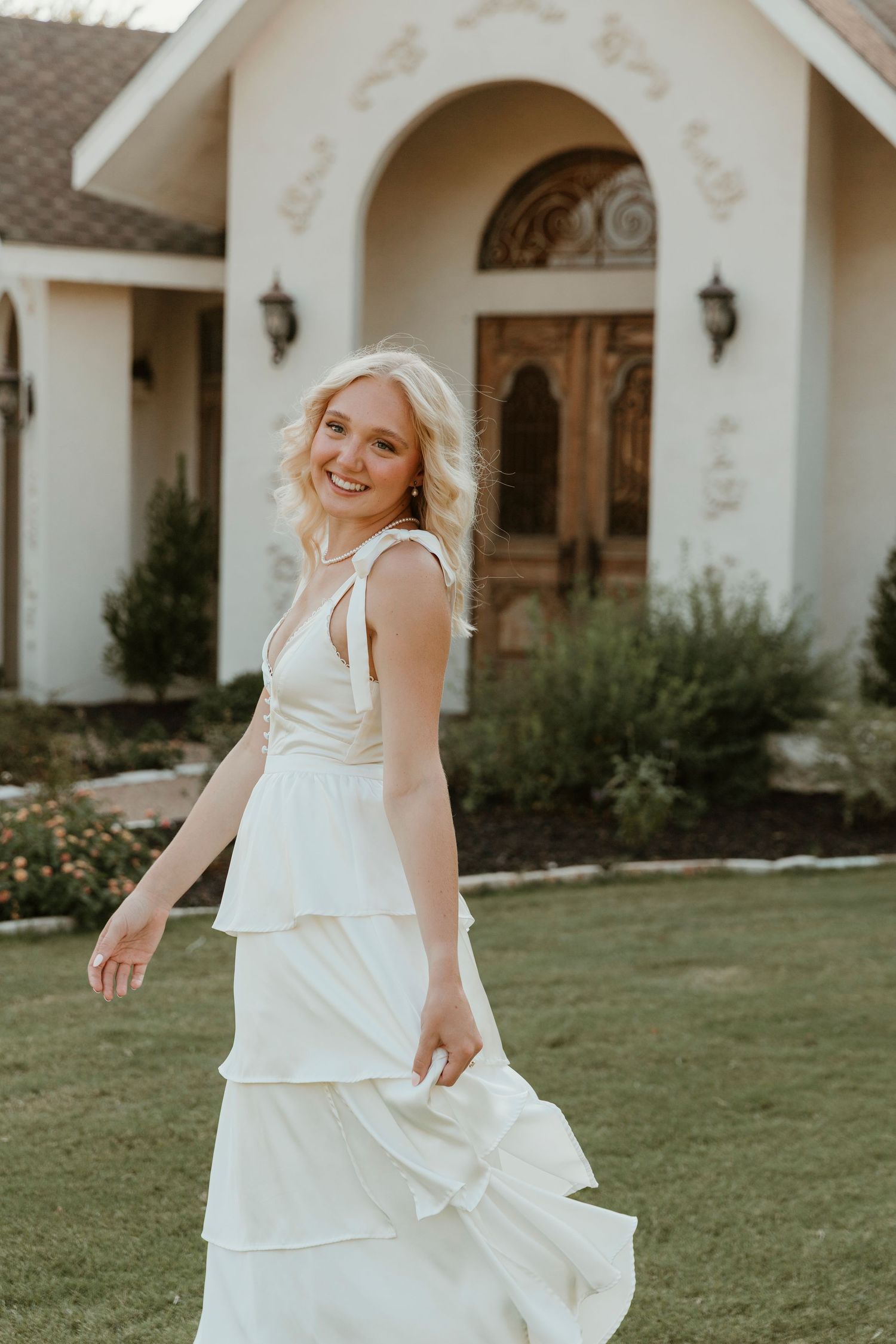 A flowing white tiered dress twirls against classic church architecture during a sunset photoshoot.