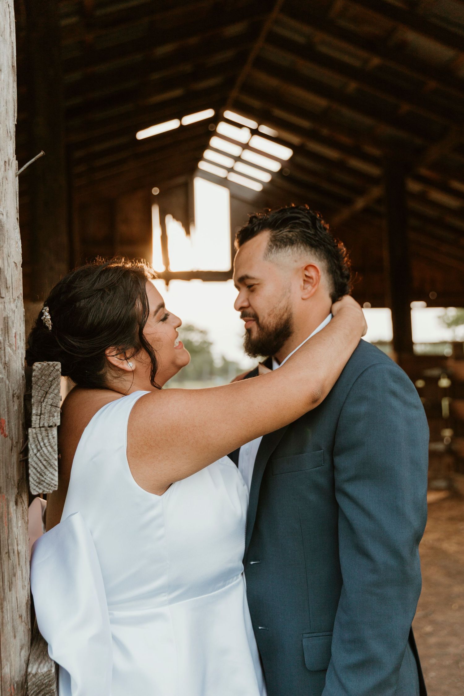 A tender romantic moment between a couple sharing a loving embrace in a rustic barn setting.