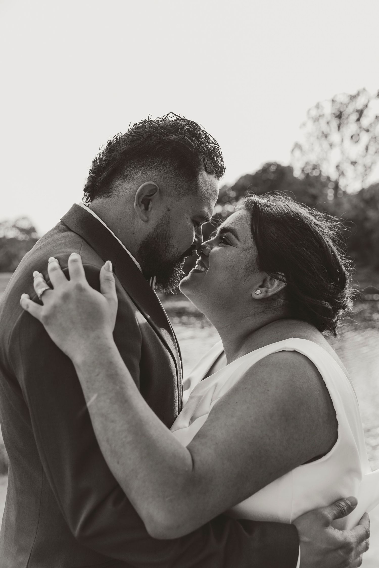 Intimate black and white portrait of a romantic couple sharing a tender moment outdoors.