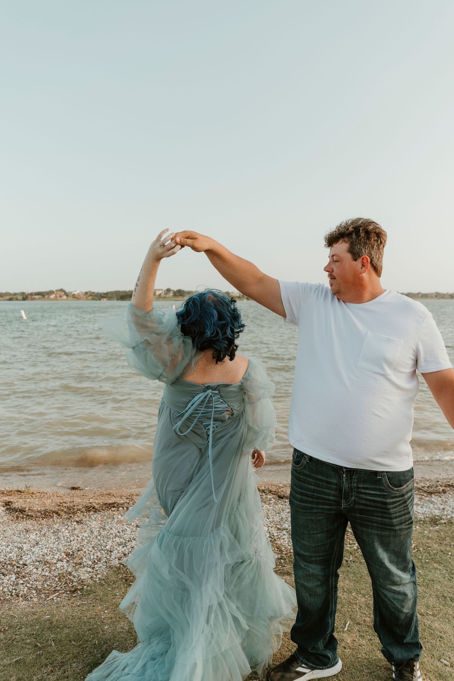 A couple shares a playful dance moment on the beach, with flowing mint dress movement.