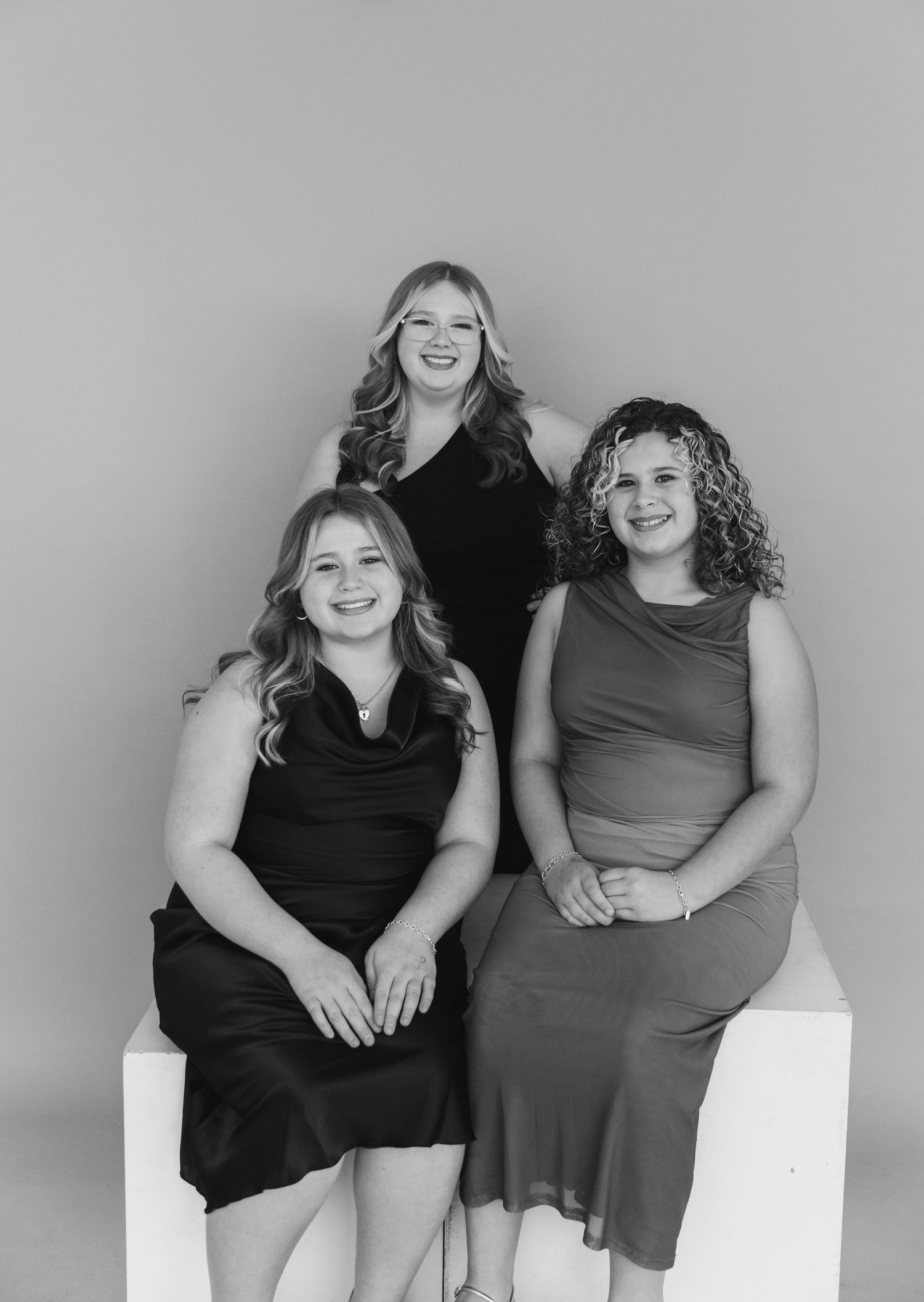A series of black and white photos showing two women in casual dresses posing together while sitting and smiling.
