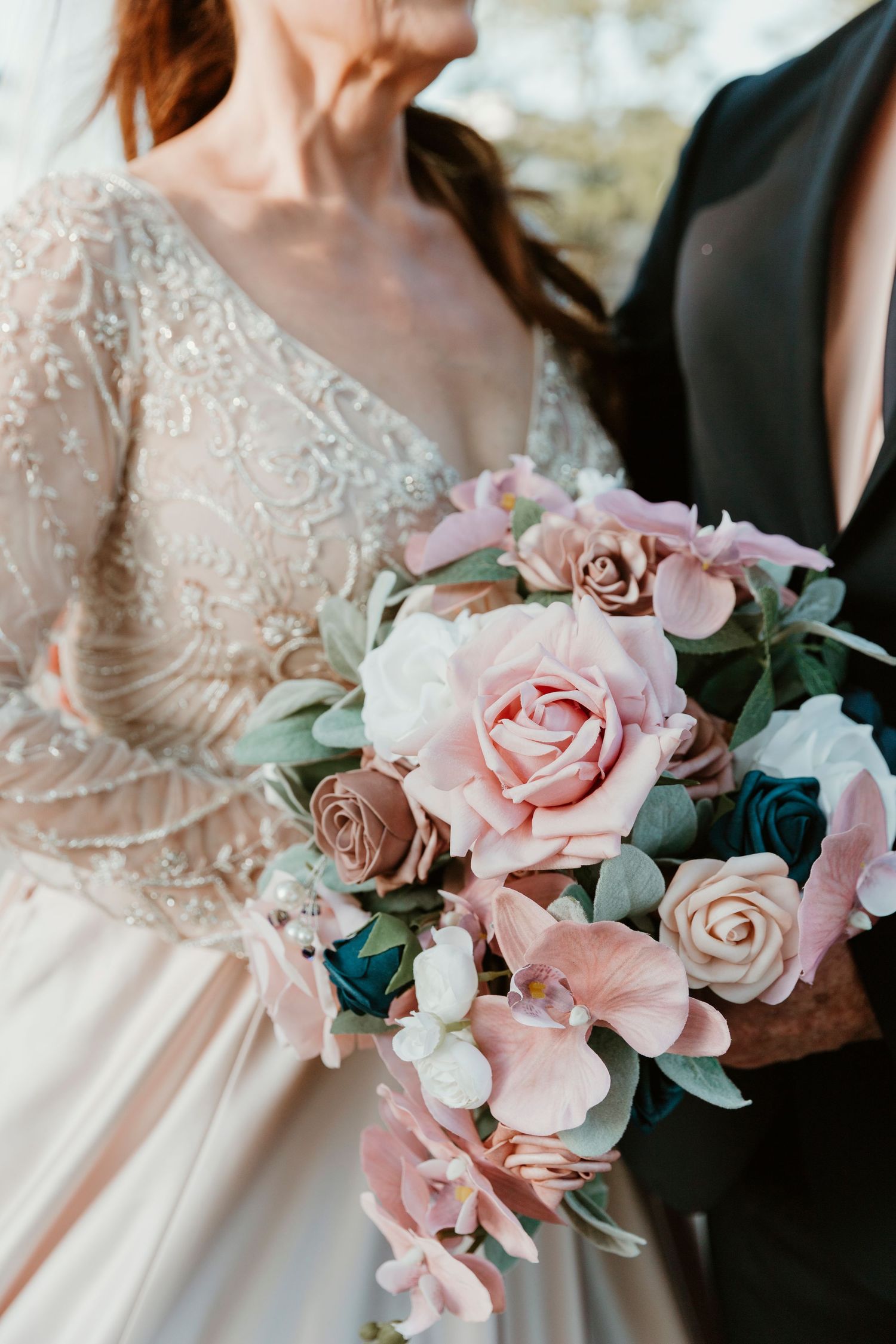 Close-up view of blush pink roses in an elegant wedding bouquet with silvery eucalyptus leaves and delicate foliage.
