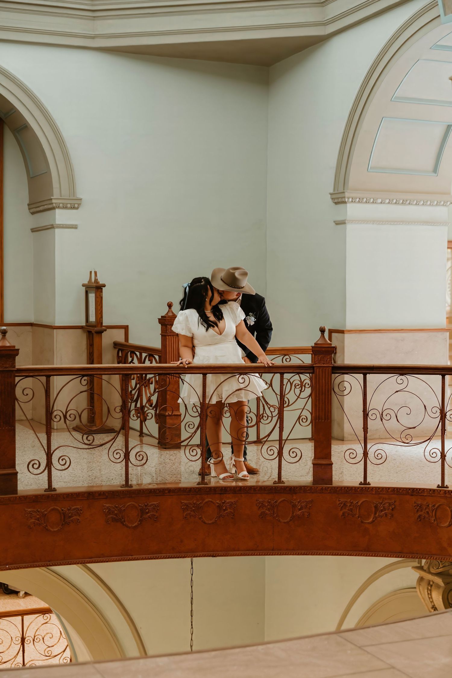 Romantic couple sharing moment on ornate balcony with classical architecture details.
