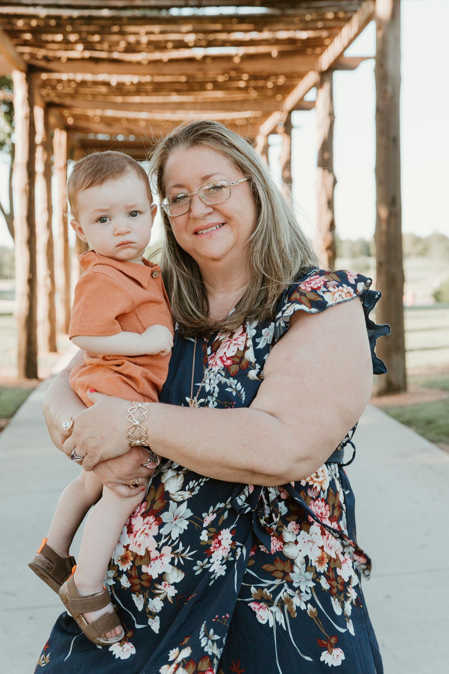 A toddler in orange clothing shares a tender moment with an adult in a floral dress.