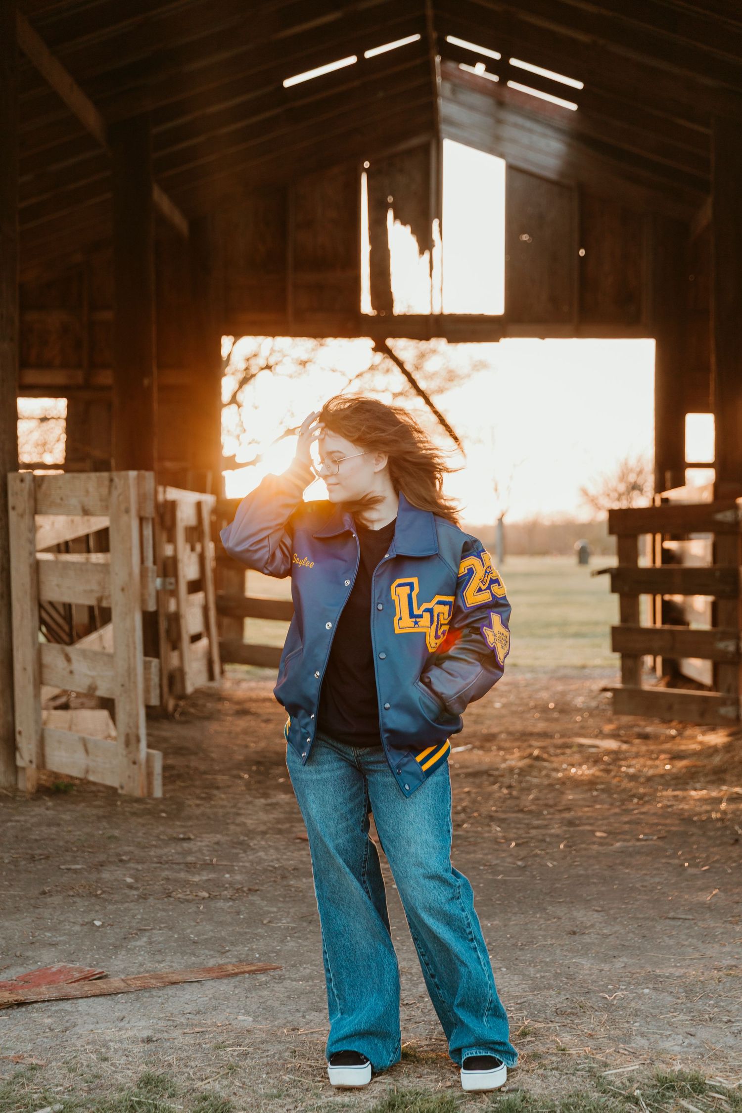 A blue letterman jacket with LC letters captured in a rustic barn with sunlight streaming through.