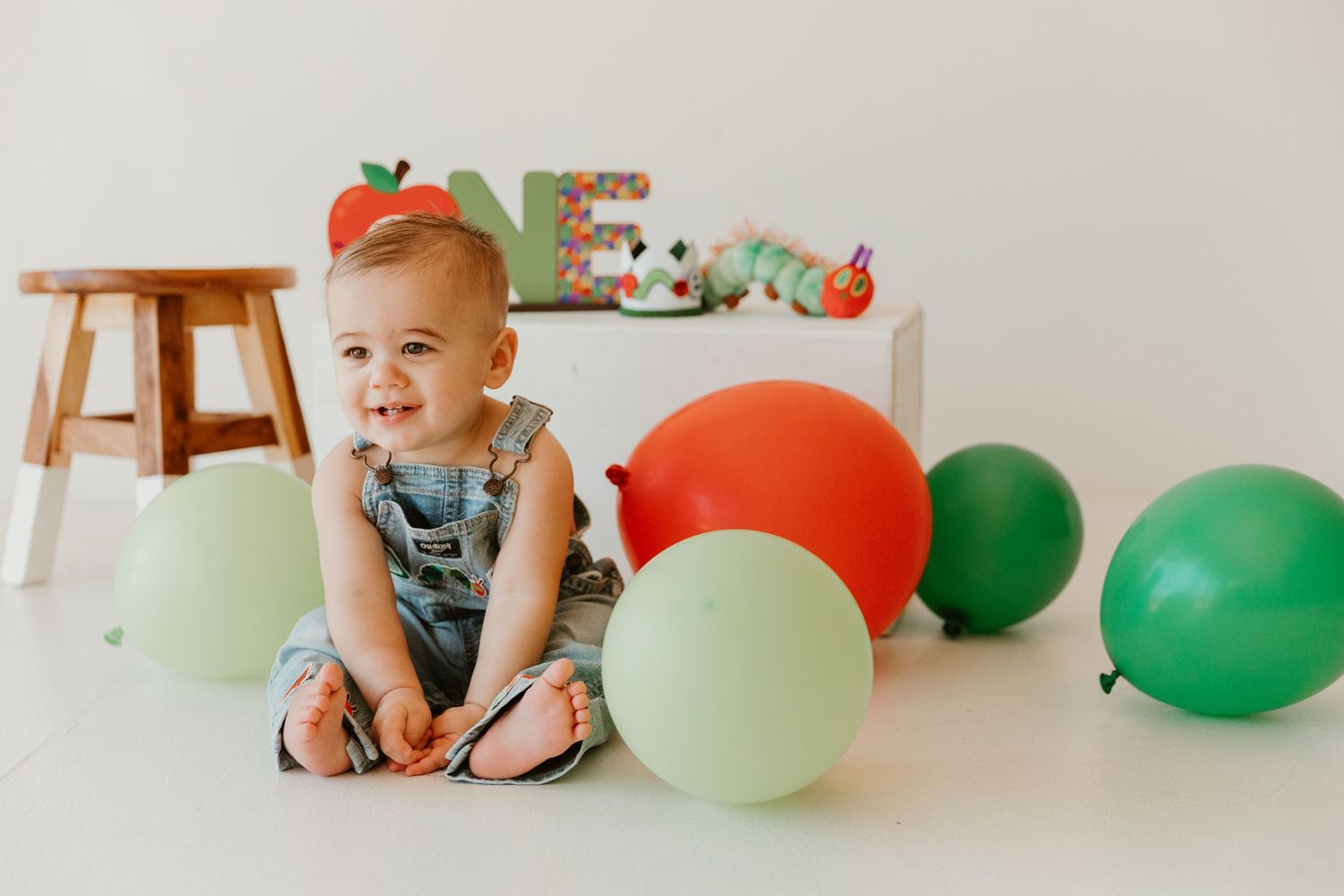 A festive birthday setup with colorful balloons and decorations against a white wall.