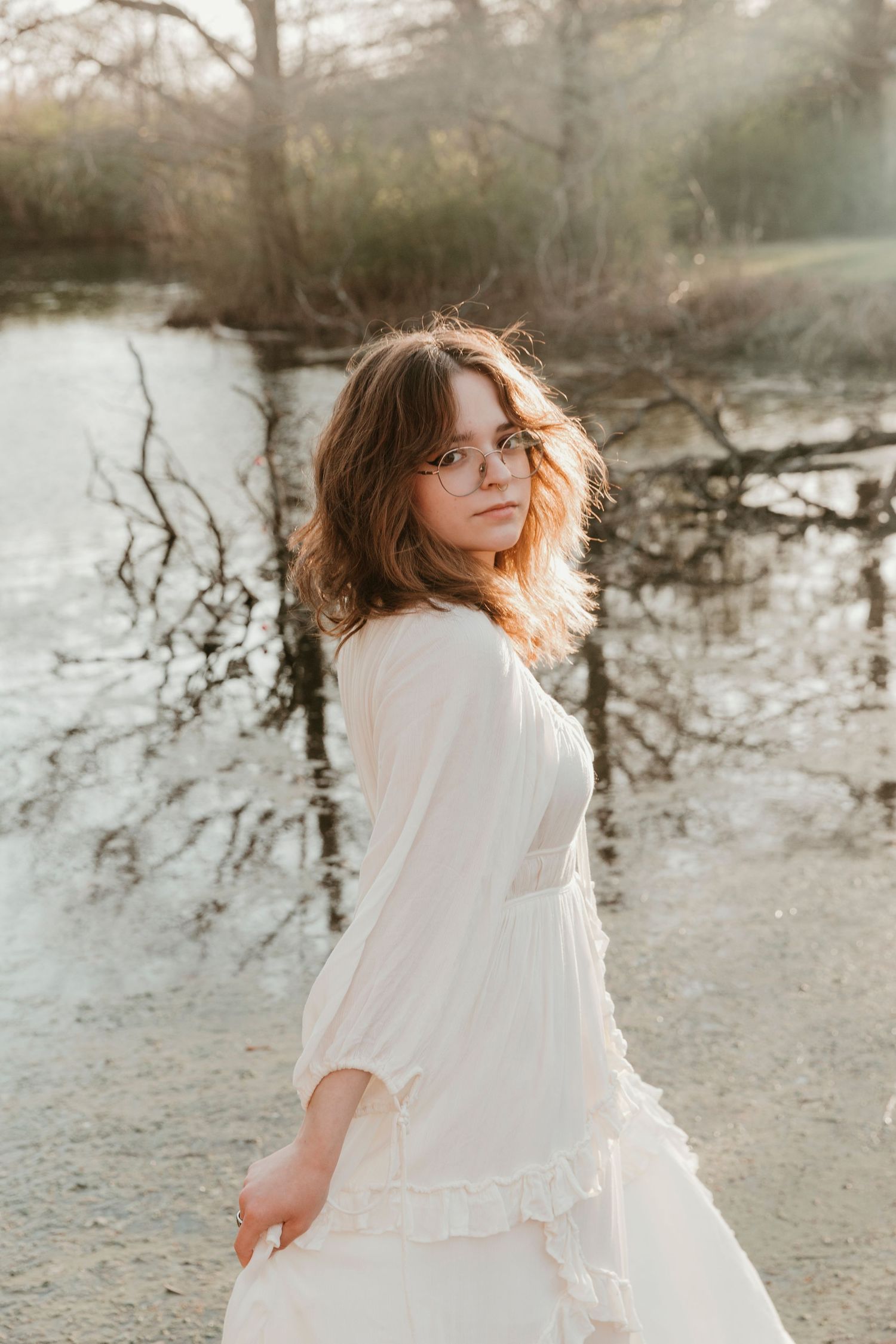 A romantic white dress photographed against a misty lake backdrop at sunset.