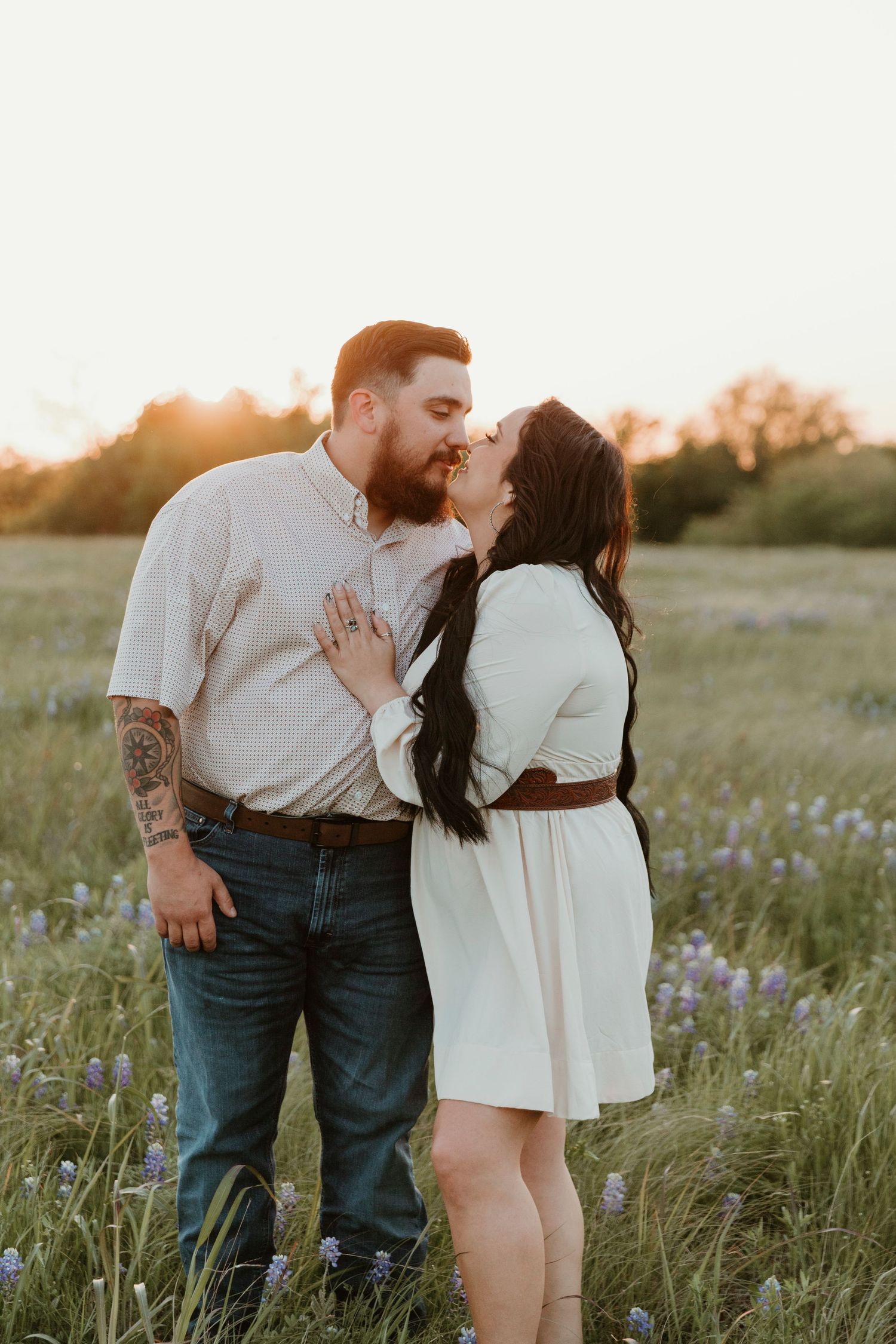 Romantic couple sharing intimate moments in a wildflower field at sunset.