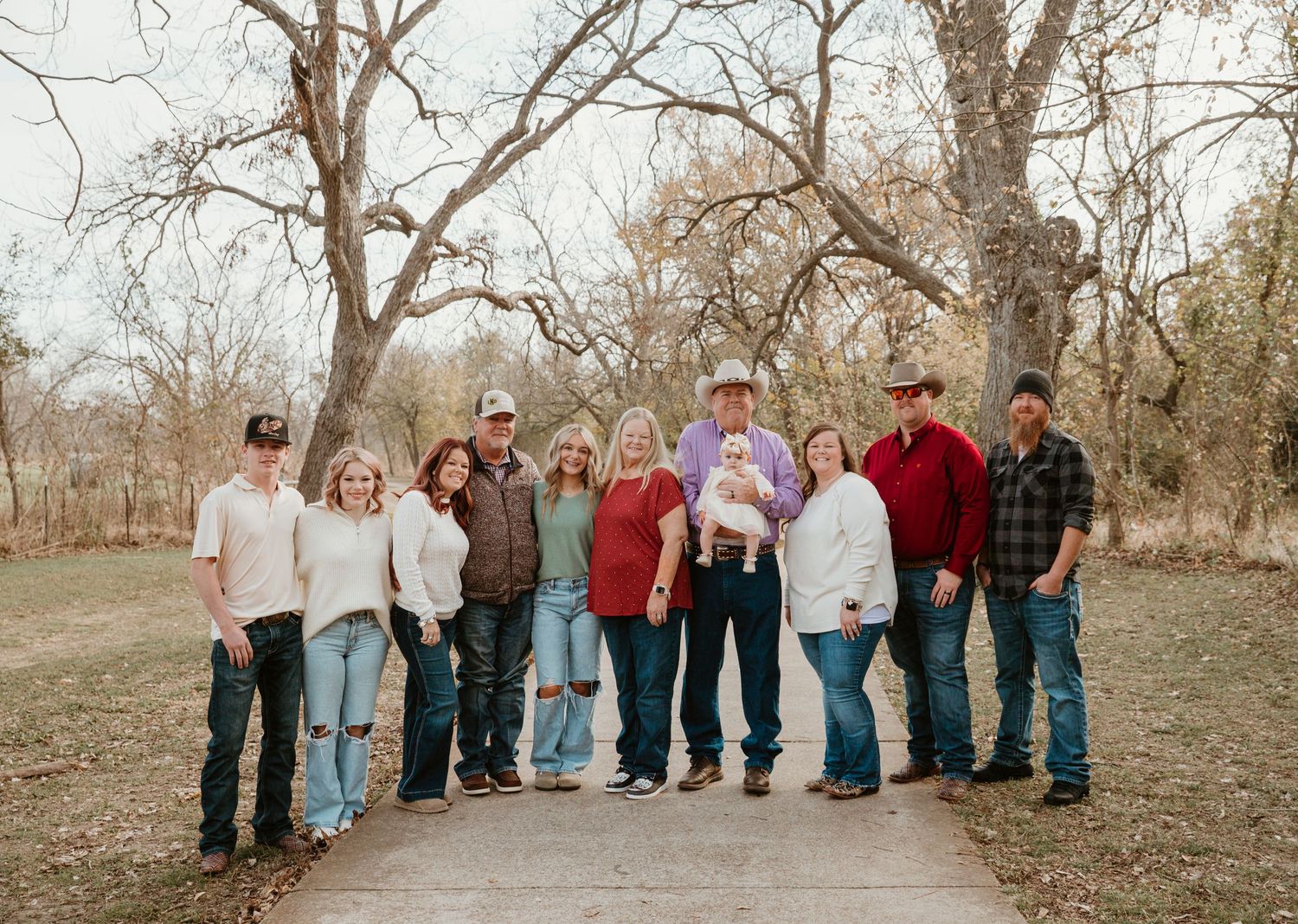 A group of people lined up in a row on a dirt path surrounded by bare trees in autumn.