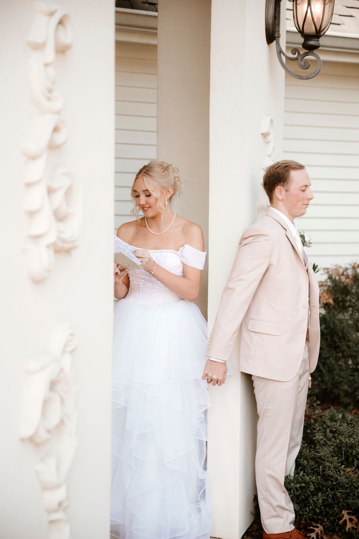 A couple shares a sweet first look moment before their wedding ceremony on a white columned porch.