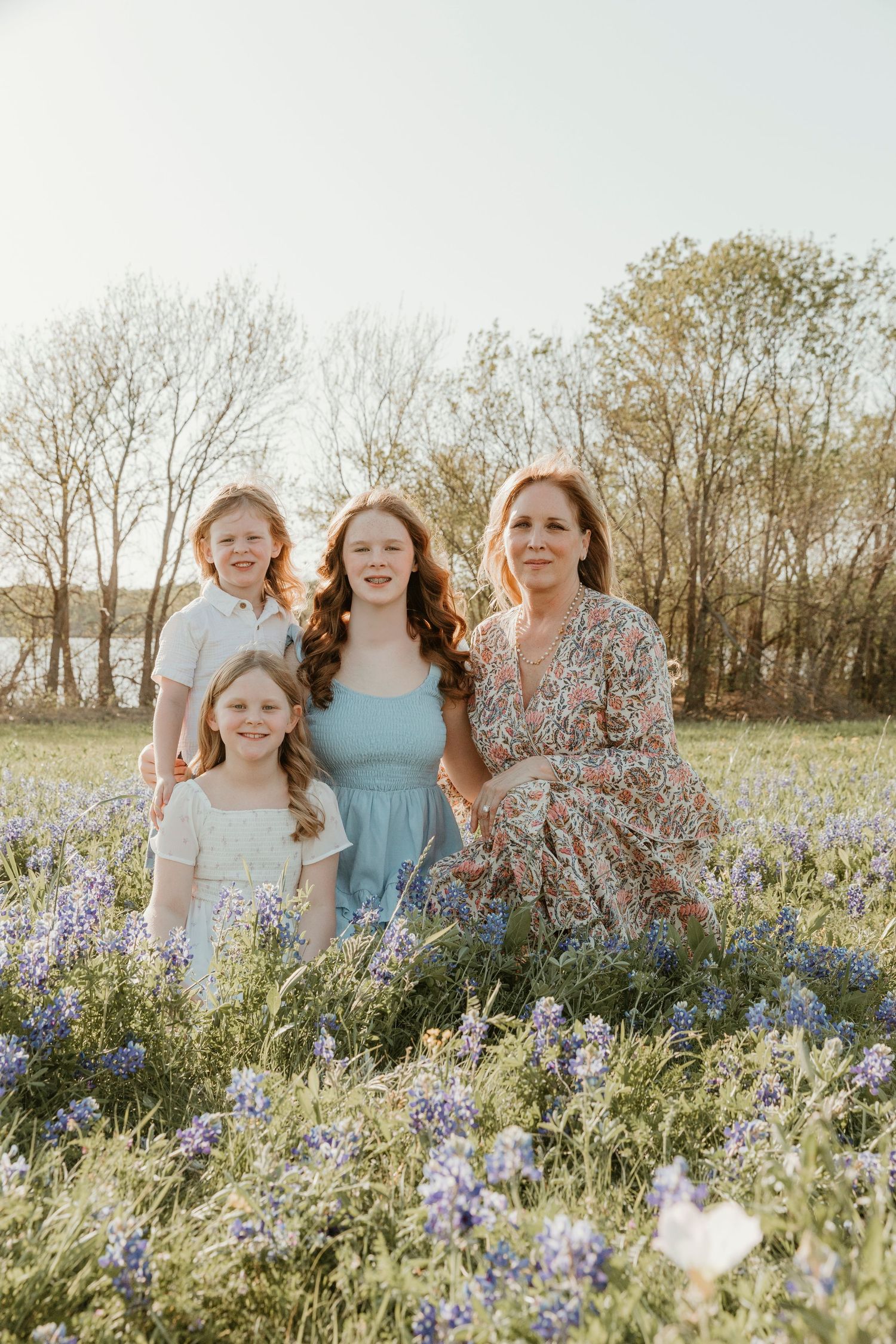Group photo of multiple generations in a field of Texas bluebonnets at sunset.