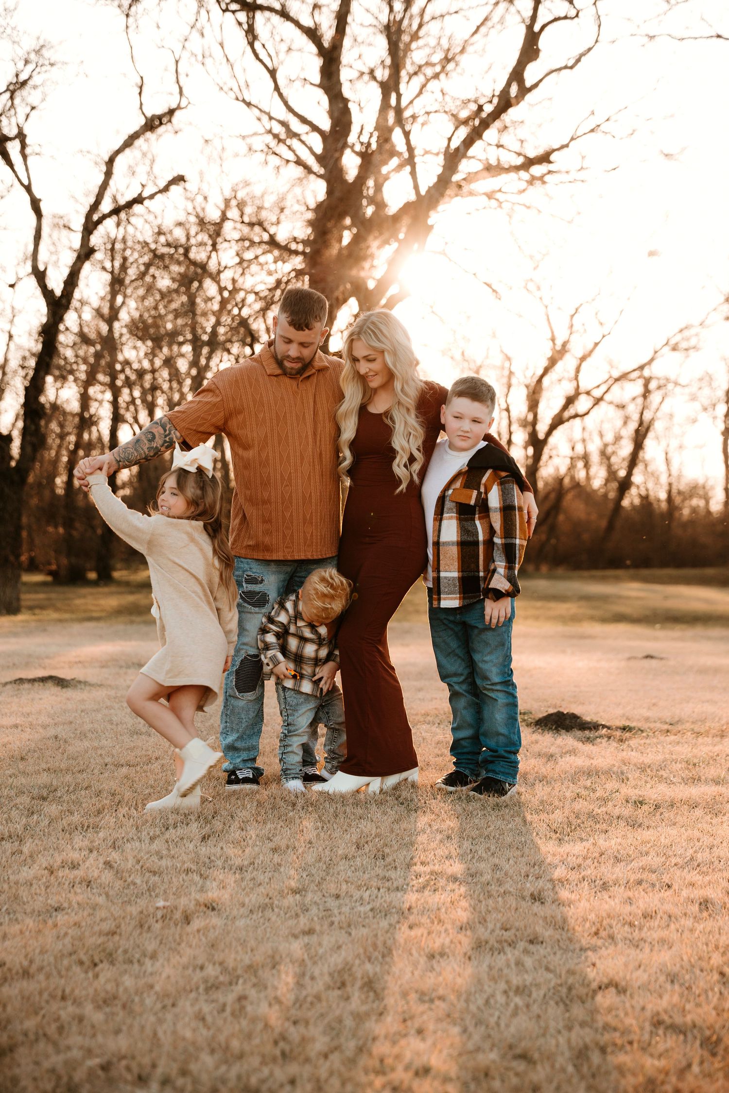 A family plays together in a grassy field at sunset creating a warm and joyful outdoor portrait series.
