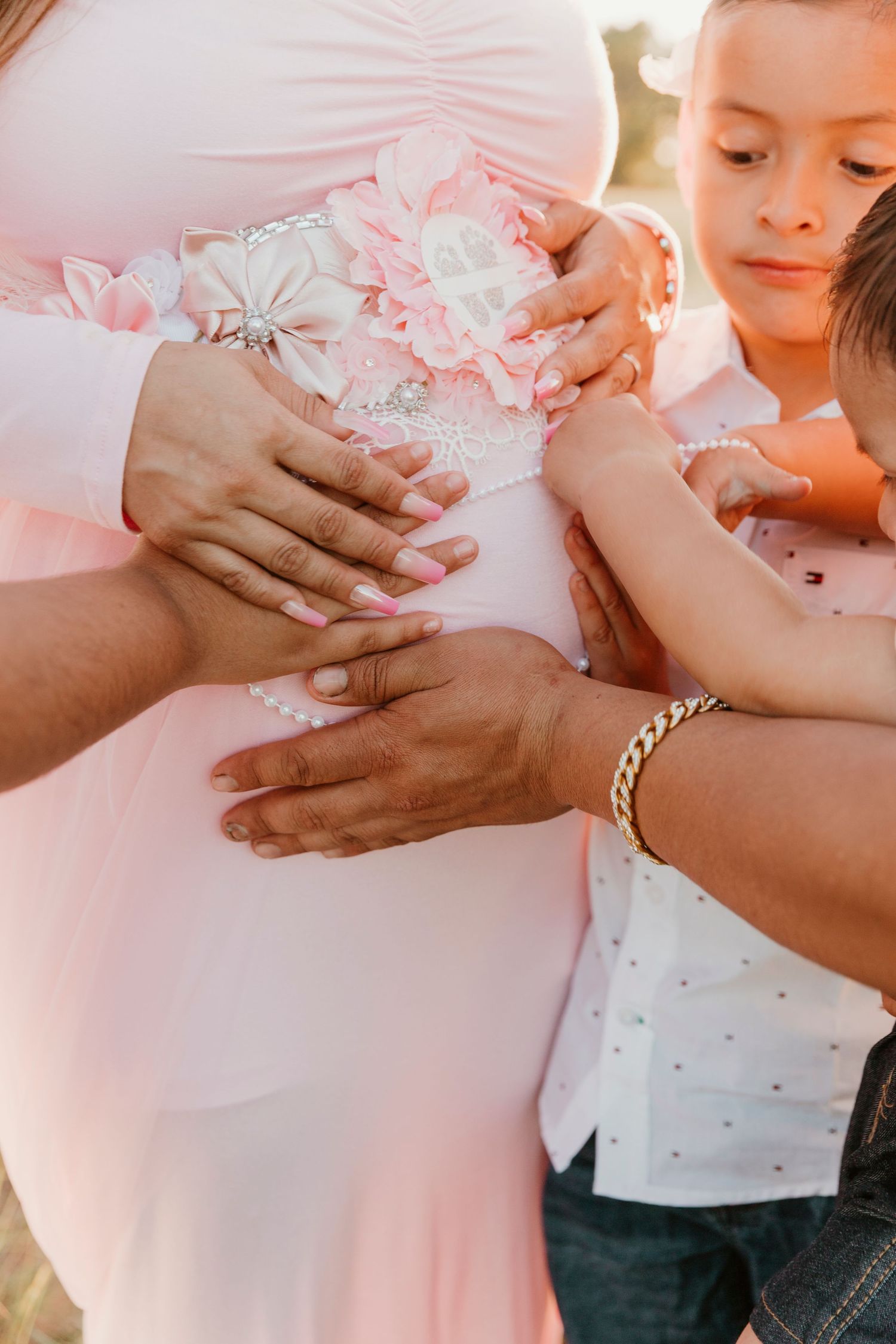 Detail shot of hands touching a pink maternity dress with floral embellishments.