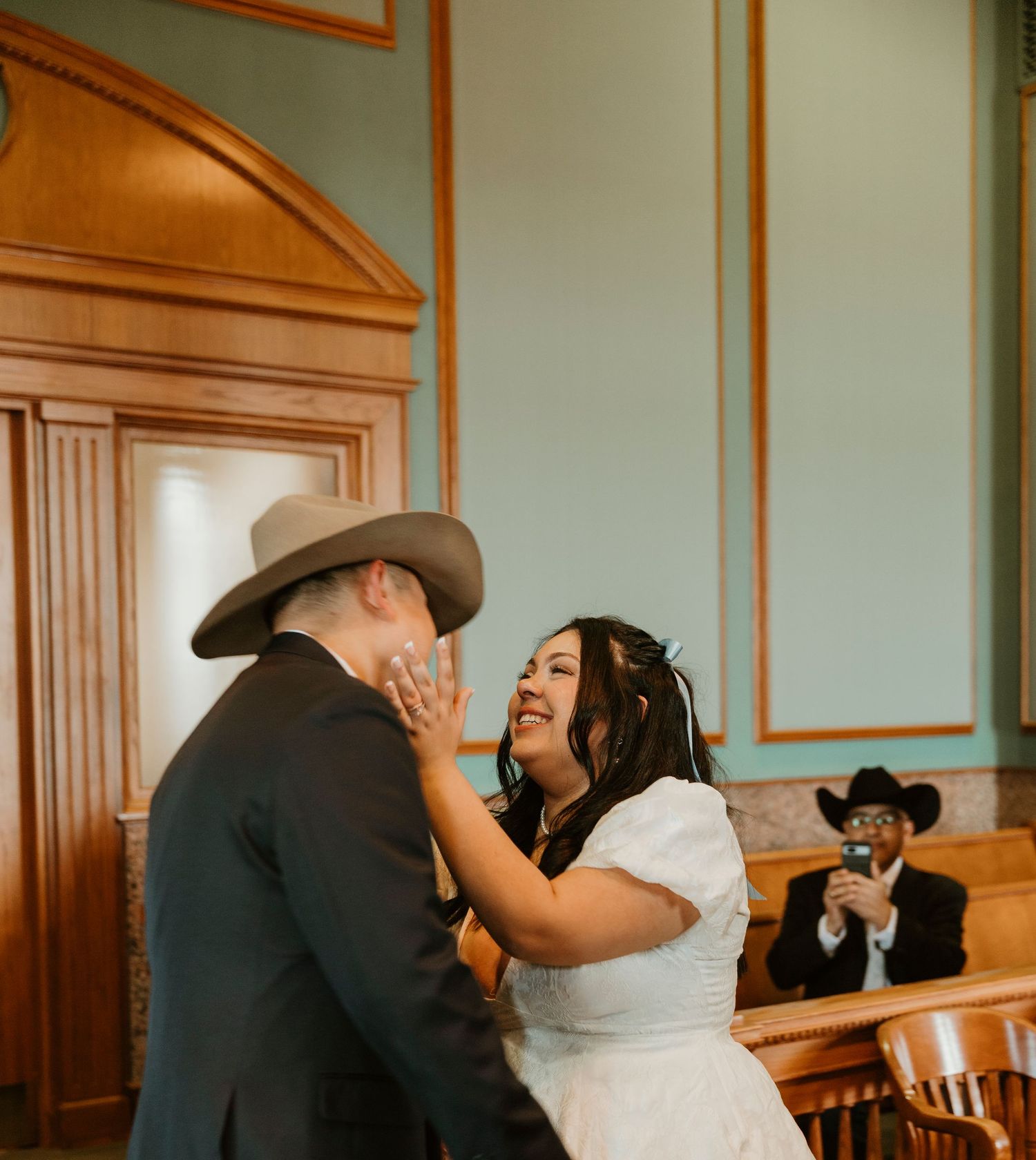 Emotional wedding moment captured in a courthouse with vintage architectural details.