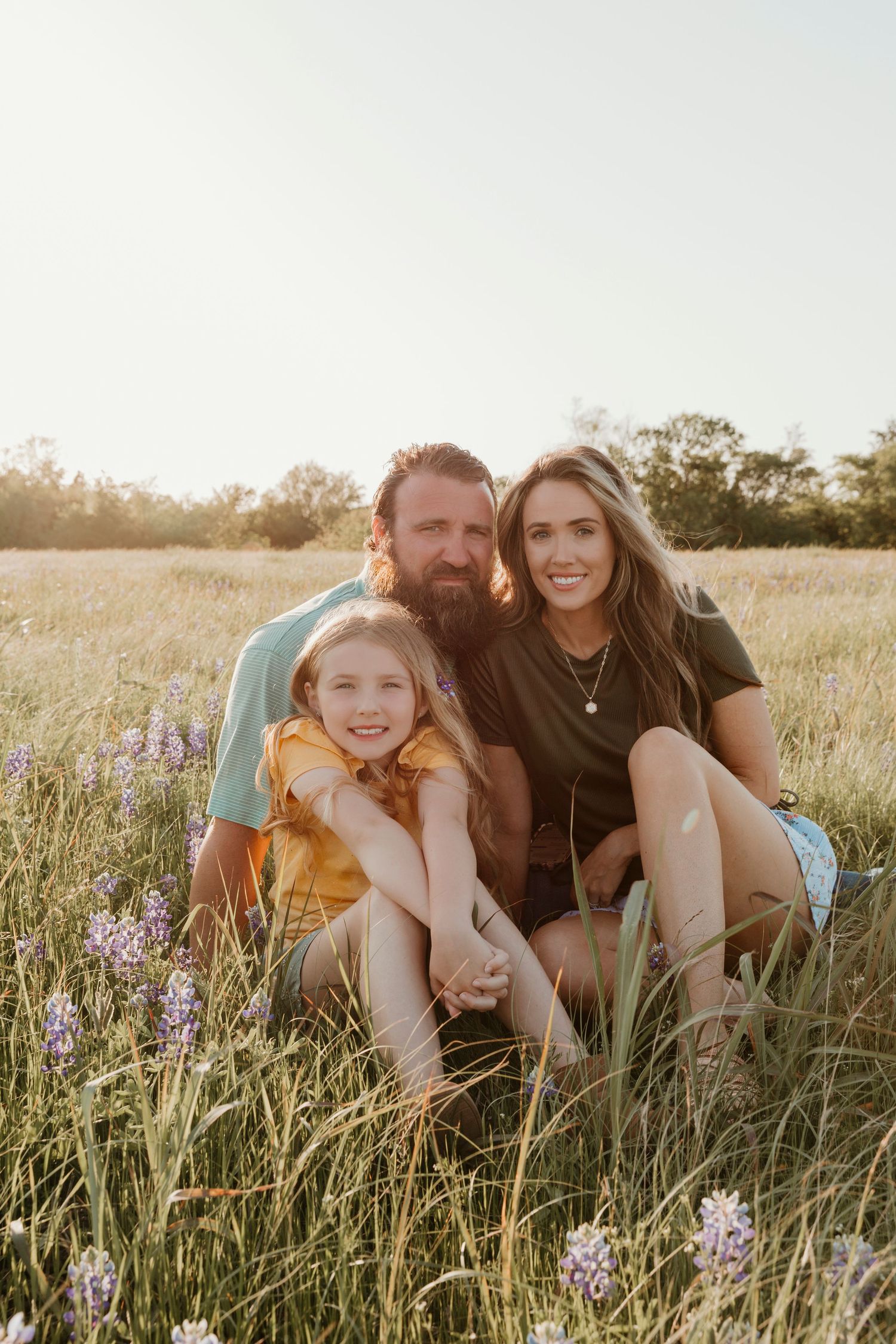 Family sitting together in a wildflower meadow at sunset.