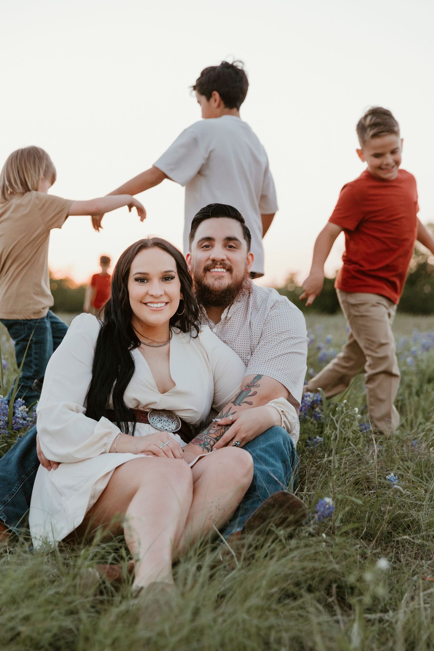Casual family moment in a field of bluebonnets during golden hour.